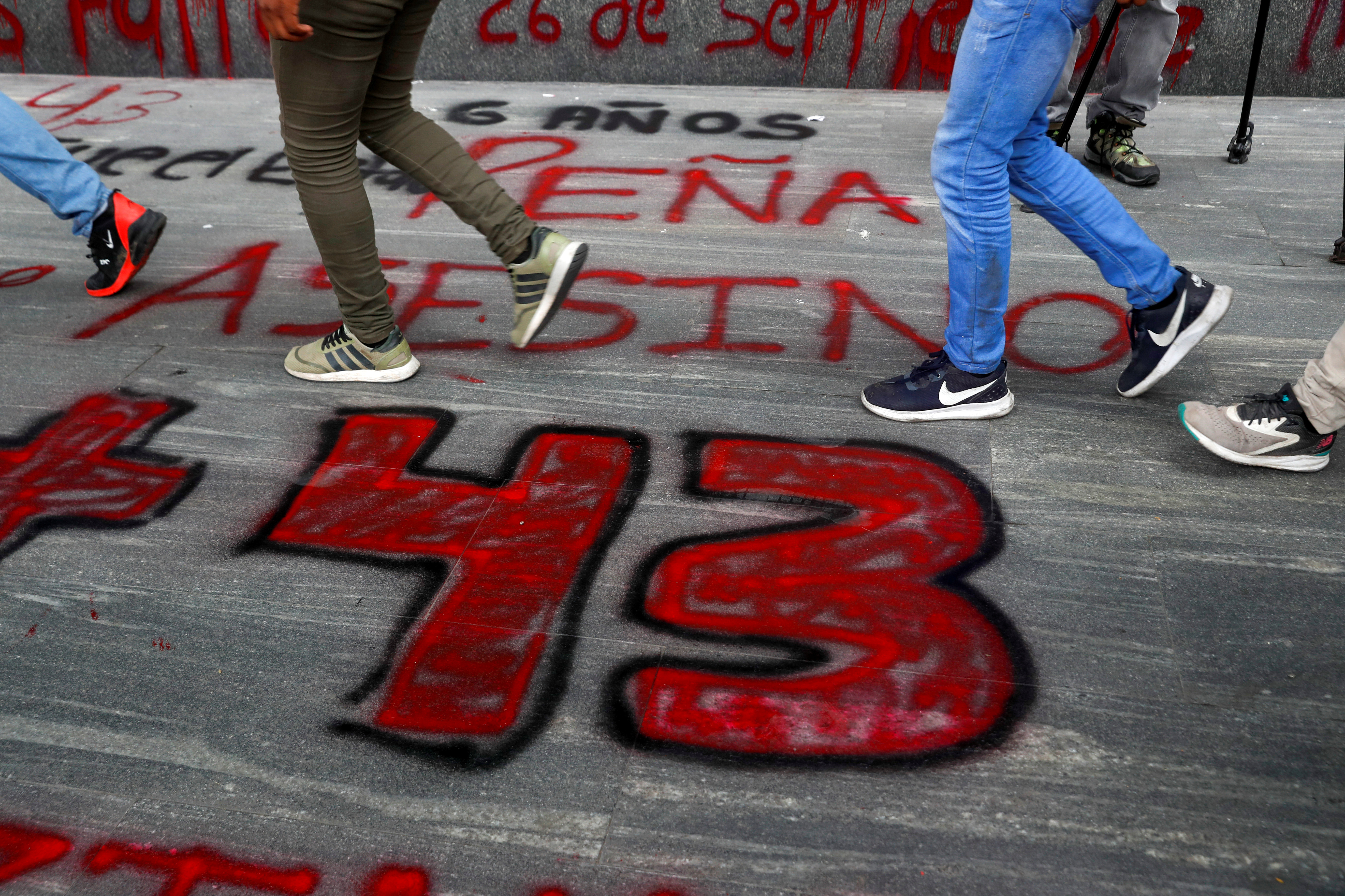 Estudiantes de la Escuela Normal Rural de Ayotzinapa pasan frente a un letrero
