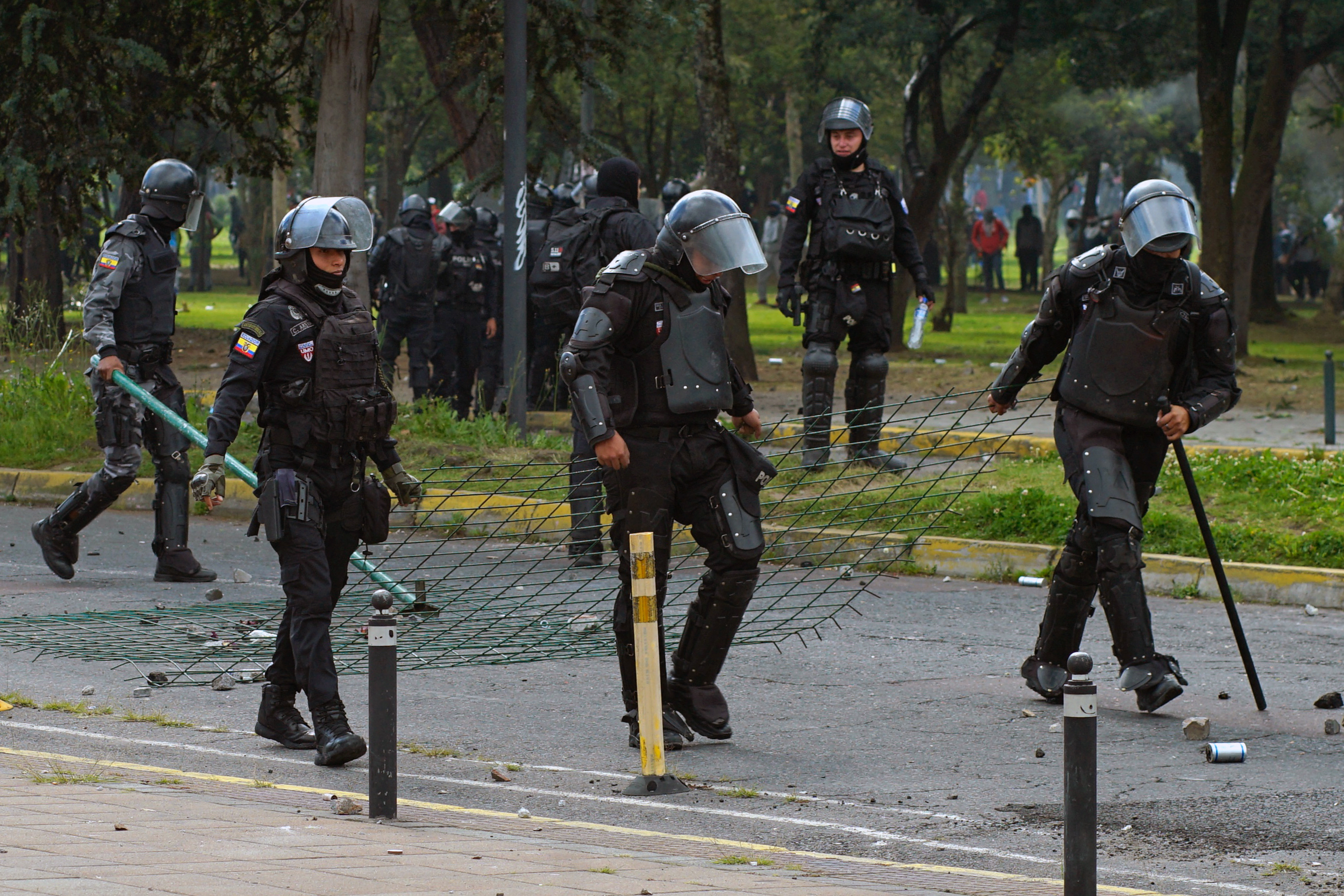 Ecuadorean riot police pull a piece of wire mesh netting while confronting demonstrators near the House of Ecuadorean Culture in Quito, on June 21, 2022, on the ninth consecutive day of protests against the government. - Police used tear gas to disperse some 500 protesters, among thousands who arrived in Quito from around the country in recent days, during the Indigenous-led fuel price protests the military described as a "grave threat." (Photo by Veronica LOMBEIDA / AFP)