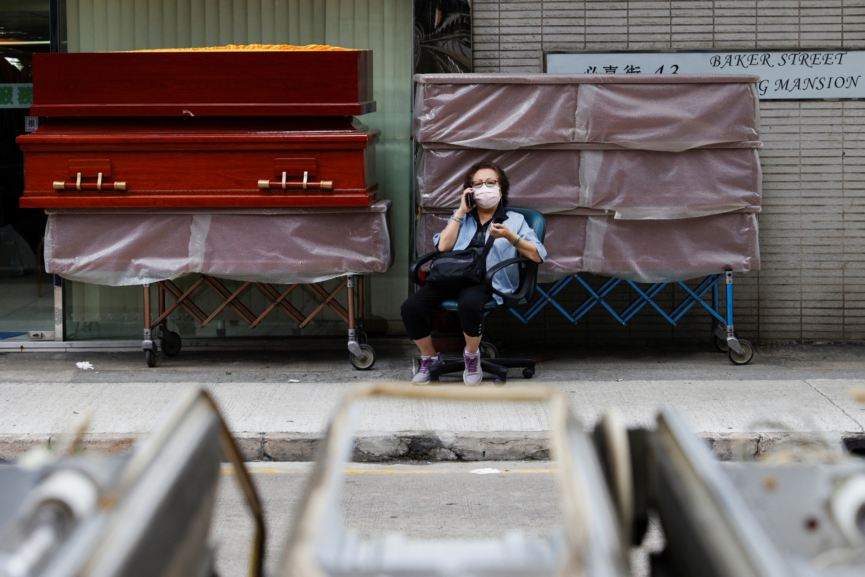 Una mujer sentada ante una pila de ataúdes en medio de la pandemia de COVID-19 en Hong Kong (REUTERS/Tyrone Siu)