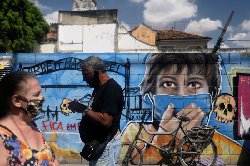 Personas con mascarillas pasan junto a un graffiti en Río de Janeiro (REUTERS/Pilar Olivares/Archivo)