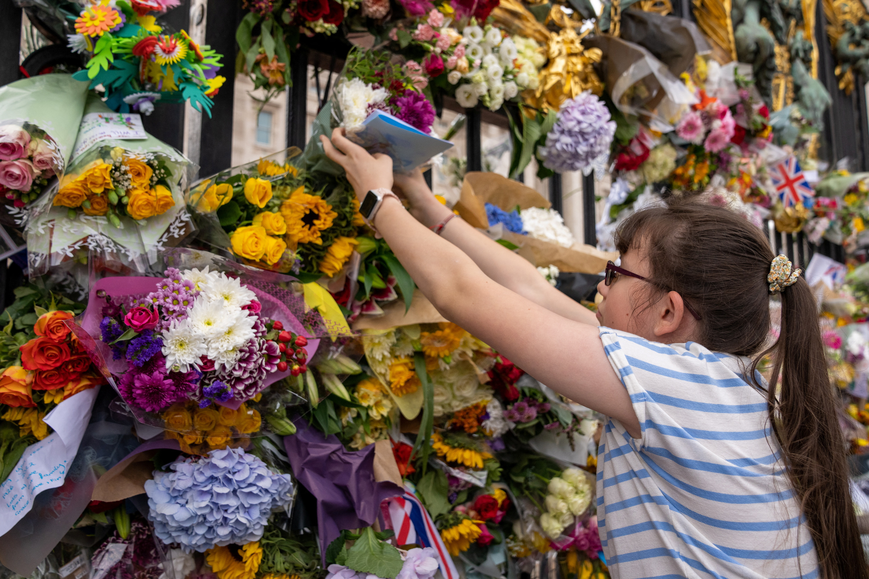 Un niña coloca flores en la puerta del Palacio Buckingham
REUTERS/Maja Smiejkowska