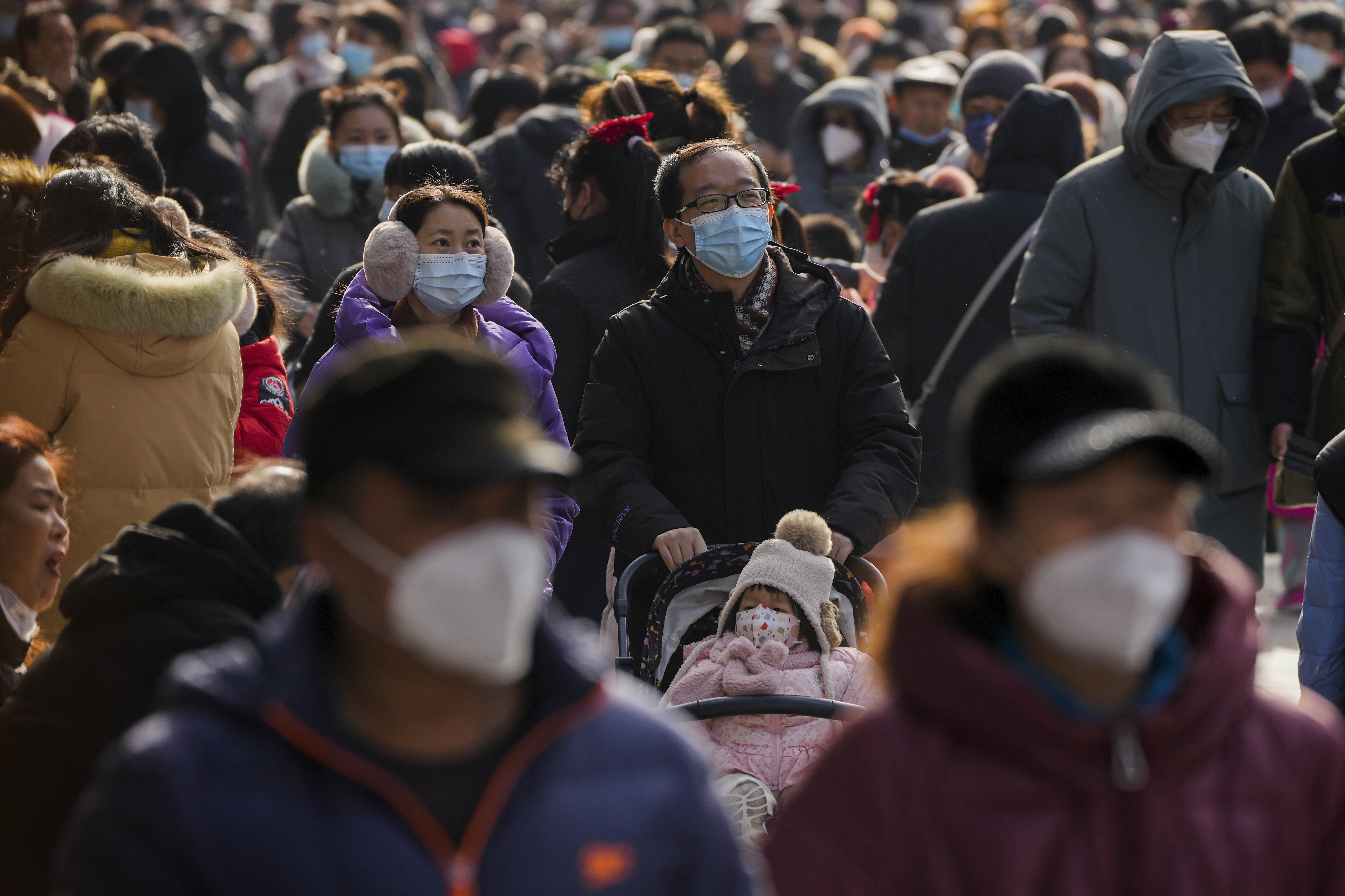 Visitors wearing face masks walk past the Qianmen pedestrian shopping street on the first day of the Lunar New Year in Beijing, Sunday, Jan. 22, 2023. People across China celebrated the turn of the year with family reunions and massive temple visits after the lifting of strict security measures "zero COVID".  (AP Photo/Andy Wong)