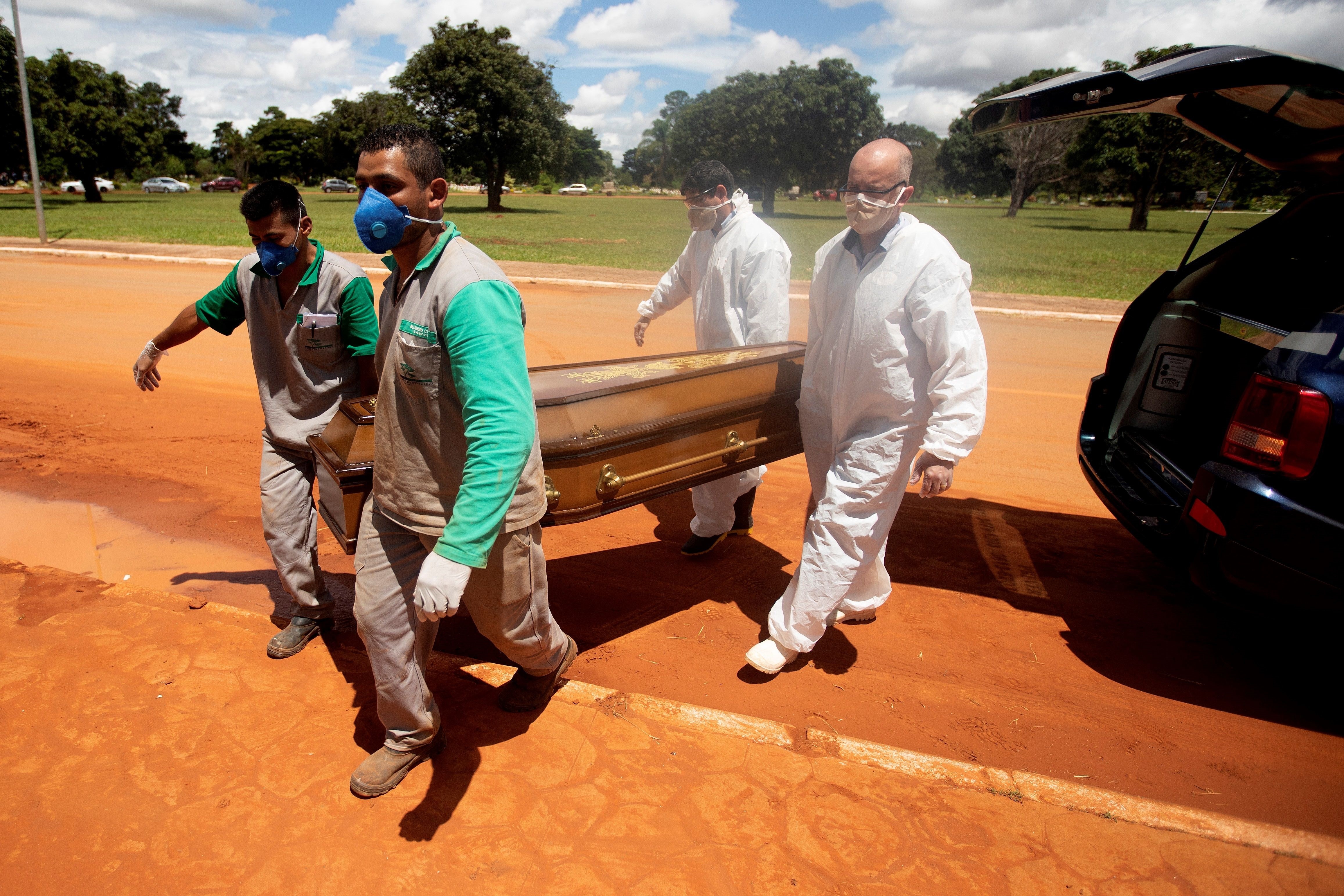 Trabajadores cargan un féretro con una víctima mortal de covid-19 rumbo a su entierro hoy, en el cementerio Campo da Esperança, en Brasilia (Brasil). EFE/ Joédson Alves
