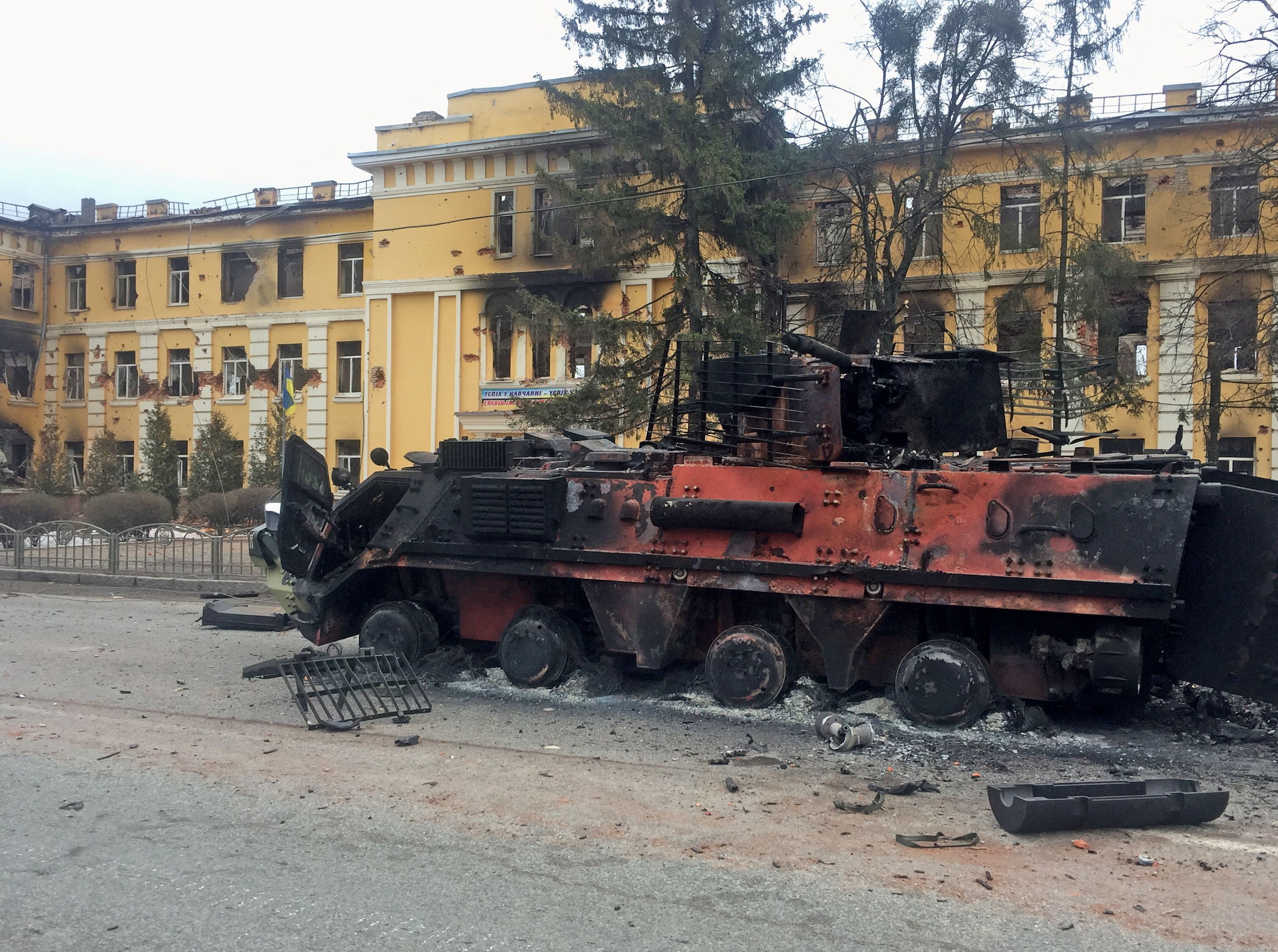 Un vehículo ucraniano de transporte de personal blindado destruido se ve delante de una escuela que, según los residentes locales, estaba en llamas después de los bombardeos, mientras la invasión de Rusia de Ucrania continúa, en Kharkiv, Ucrania 28 de febrero de 2022. REUTERS/Vitaliy Gnidyi
