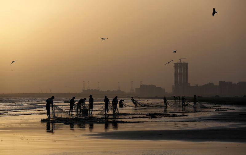 FOTO DE ARCHIVO. Imagen referencial de pescadores limpiando sus redes en la desierta playa de Clifton, en Karachi, Pakistán. 16 de mayo de 2020. REUTERS/Akhtar Soomro