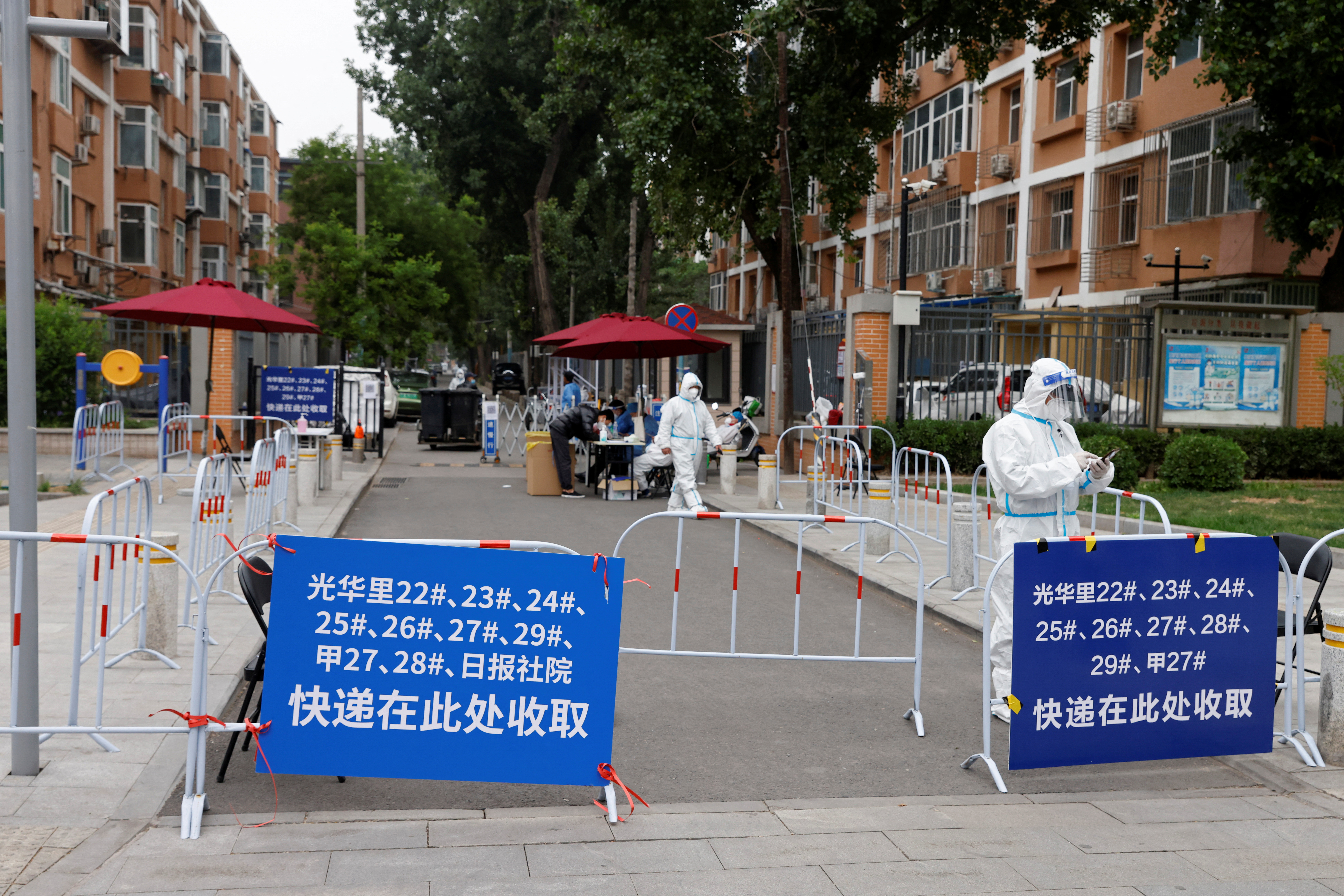 Trabajadores con trajes de protección son vistos en una entrada bloqueada a una zona residencial bajo cierre, en medio del brote de la enfermedad del coronavirus (COVID-19) en Beijing, China 10 de mayo de 2022. REUTERS/Carlos García Rawlins
