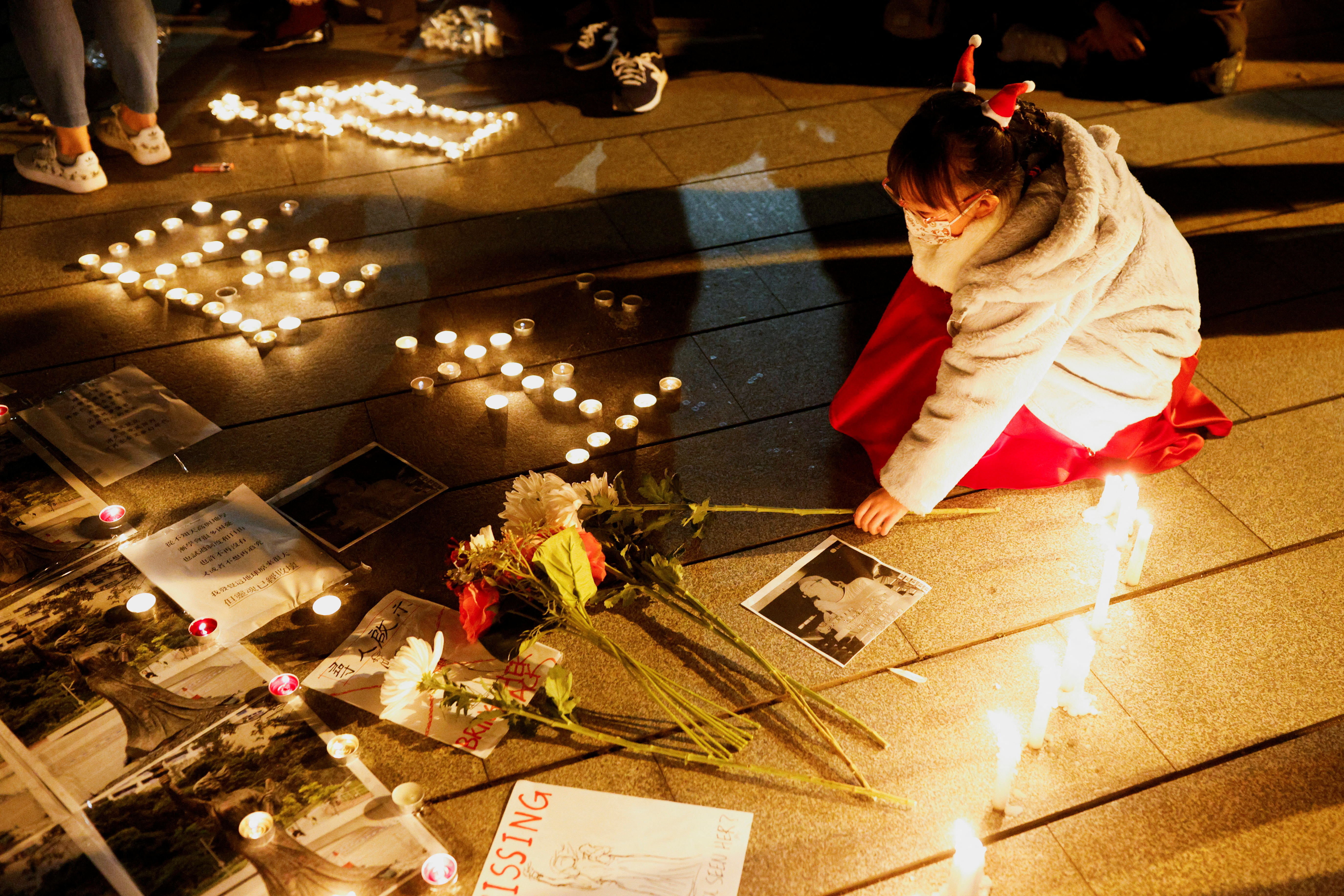 Una niña coloca un ramo de flores para rendir homenaje a las víctimas de la represión de la Plaza de Tiananmen en Beijing el 4 de junio de 1989, en el lugar donde solía estar la estatua de la Diosa de la Democracia, en la universidad china de Hong Kong, después de que fue removida por autoridad escolar, en Hong Kong, China, 24 de diciembre de 2021. REUTERS/Tyrone Siu
