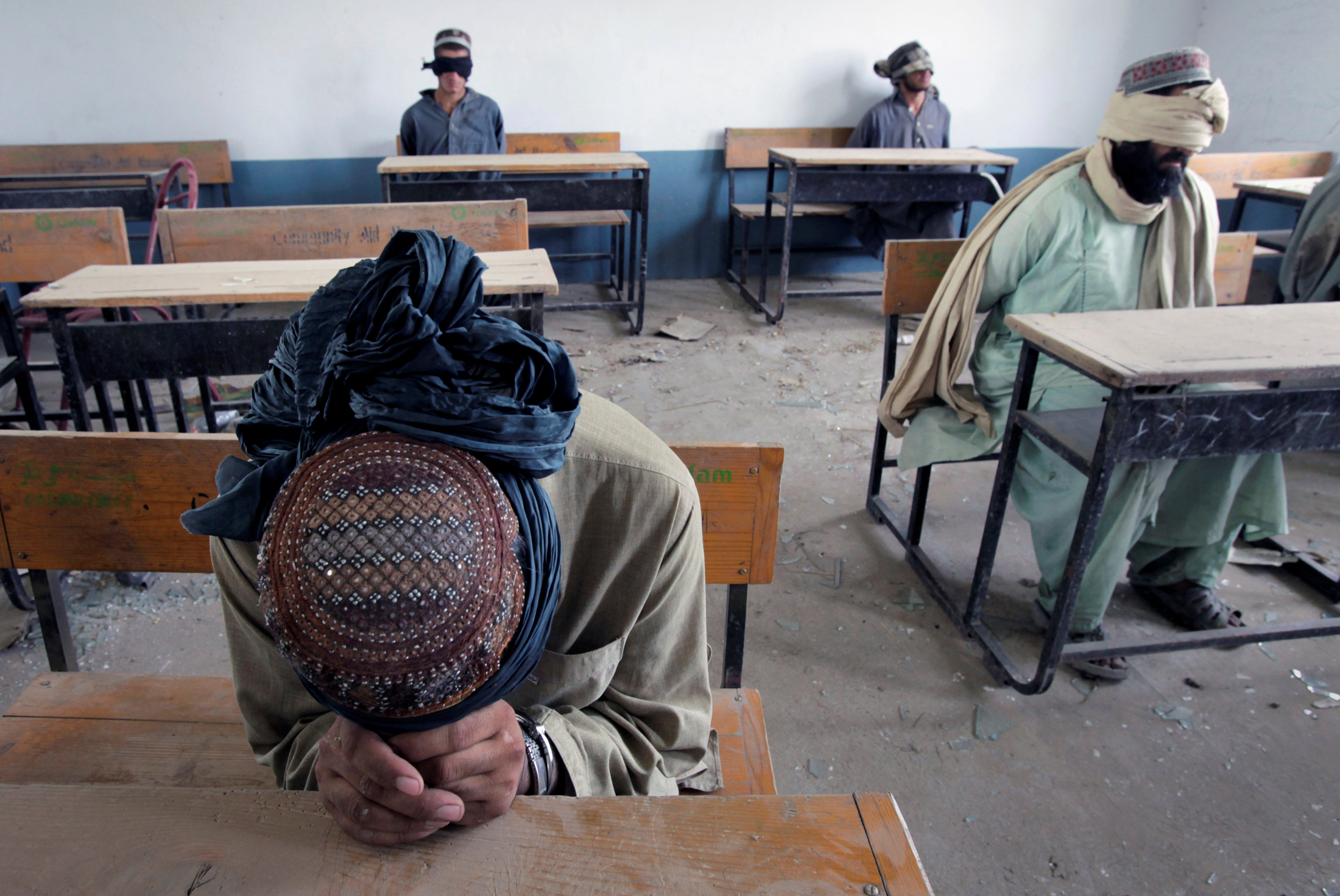 Un grupo de hombres detenidos por presuntas actividades de los talibanes son retenidos para ser interrogados en una escuela en la aldea de Kuhak en el distrito de Arghandab, al norte de Kandahar, Afganistán, el 9 de julio de 2010. (REUTERS / Bob Strong / Foto de archivo)