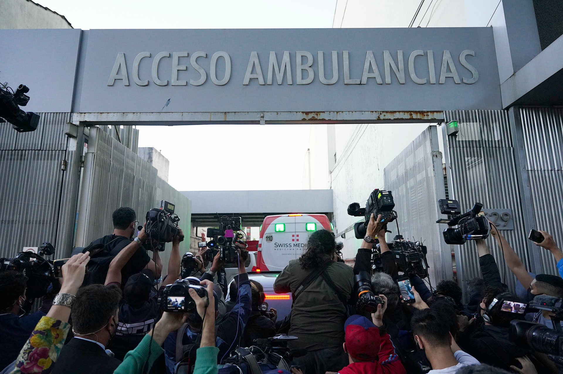Una pared de fotógrafos y cámaras toman el ingreso de la ambulancia a la Clínica Olivos