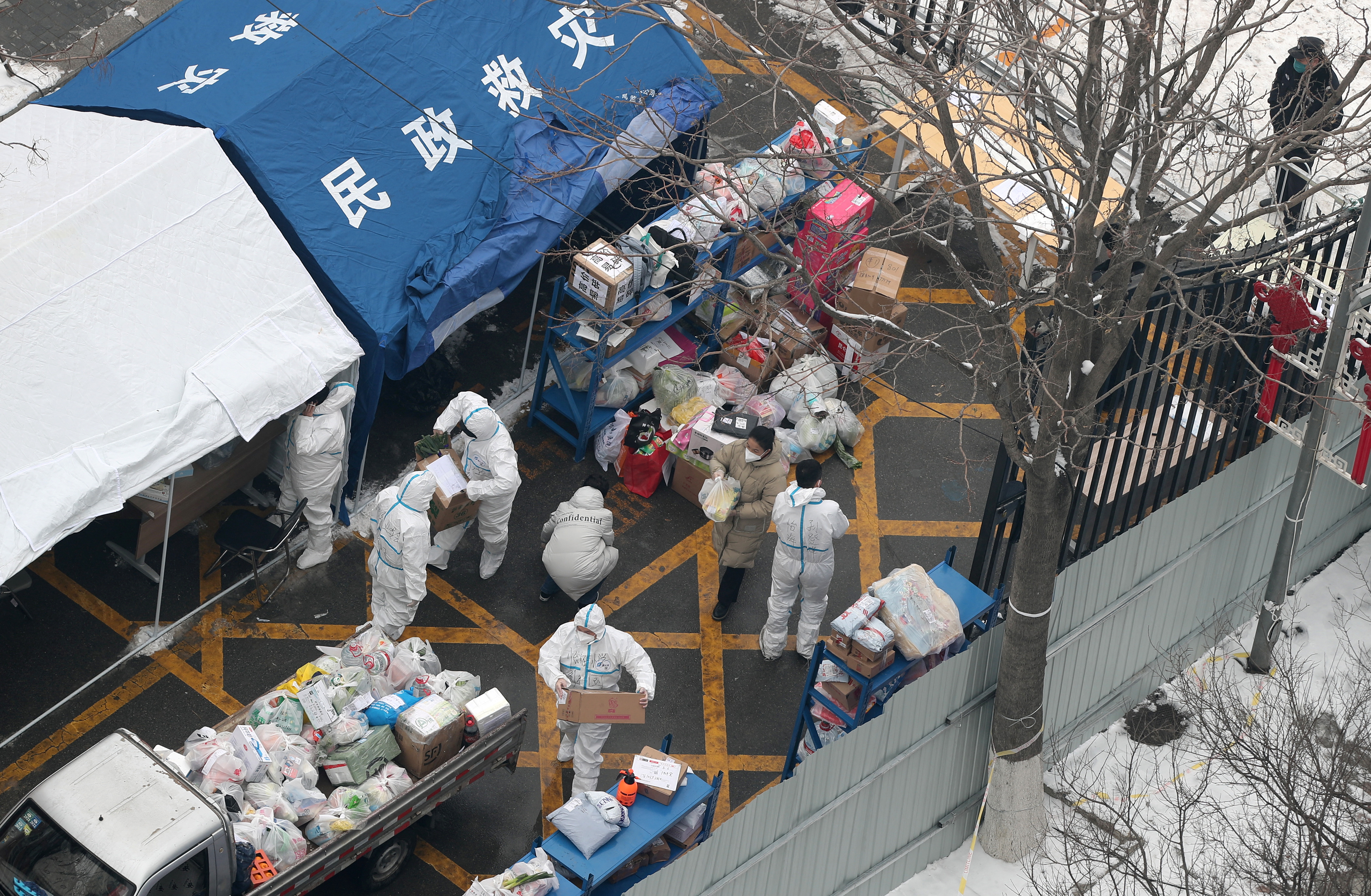 Trabajadores con trajes protectores clasifican los suministros que se entregarán a los residentes en un complejo cerrado luego de casos de la enfermedad coronavirus (COVID-19), en el distrito de Fengtai de Beijing, China, el 23 de enero de 2022. Foto tomada el 23 de enero de 2022. cnsphoto vía REUTERS