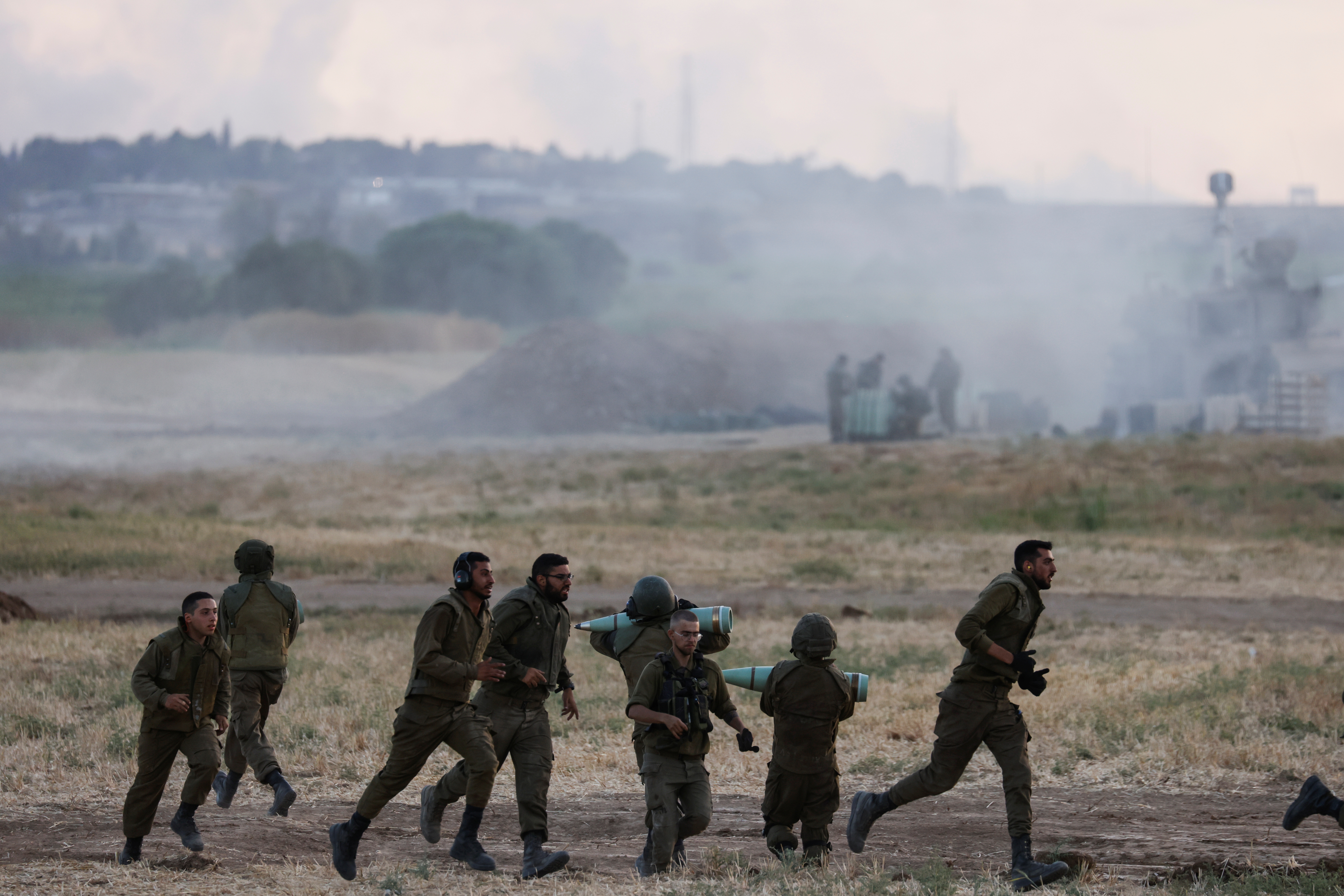 Israeli soldiers carry artillery shells and run in a field near the border between Israel and the Gaza Strip, on its Israeli side May 17, 2021. REUTERS/Amir Cohen