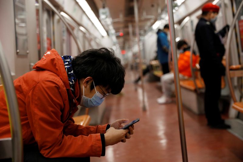 Un hombre con mascarilla revisa su teléfono móvil mientras viaja en metro por la mañana después del prolongado día festivo del Año Nuevo Lunar causado por el novedoso brote de coronavirus, en Beijing, China, el 10 de febrero de 2020. REUTERS/Carlos Garcia Rawlins/Archivo