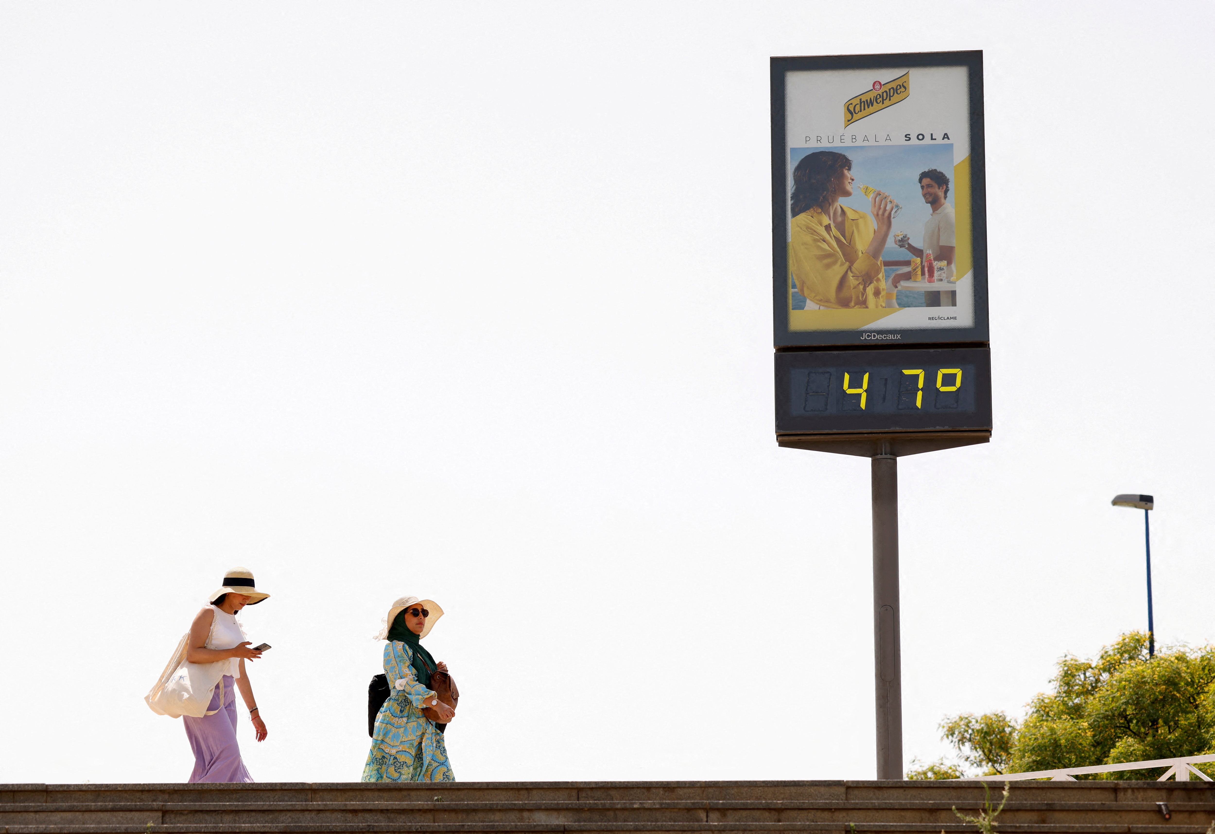 FOTO DE ARCHIVO: Mujeres caminan junto a un termómetro que marca 47 grados Celsius (116,6 grados Fahrenheit) durante la primera ola de calor del año en Sevilla, España, el 11 de junio de 2022. REUTERS/Marcelo del Pozo/Foto de archivo