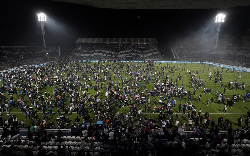 Fans affected by tear gas invade the field after the match between Gimnasia y Esgrima La Plata and Boca Juniors was suspended (REUTERS / José Brusco)