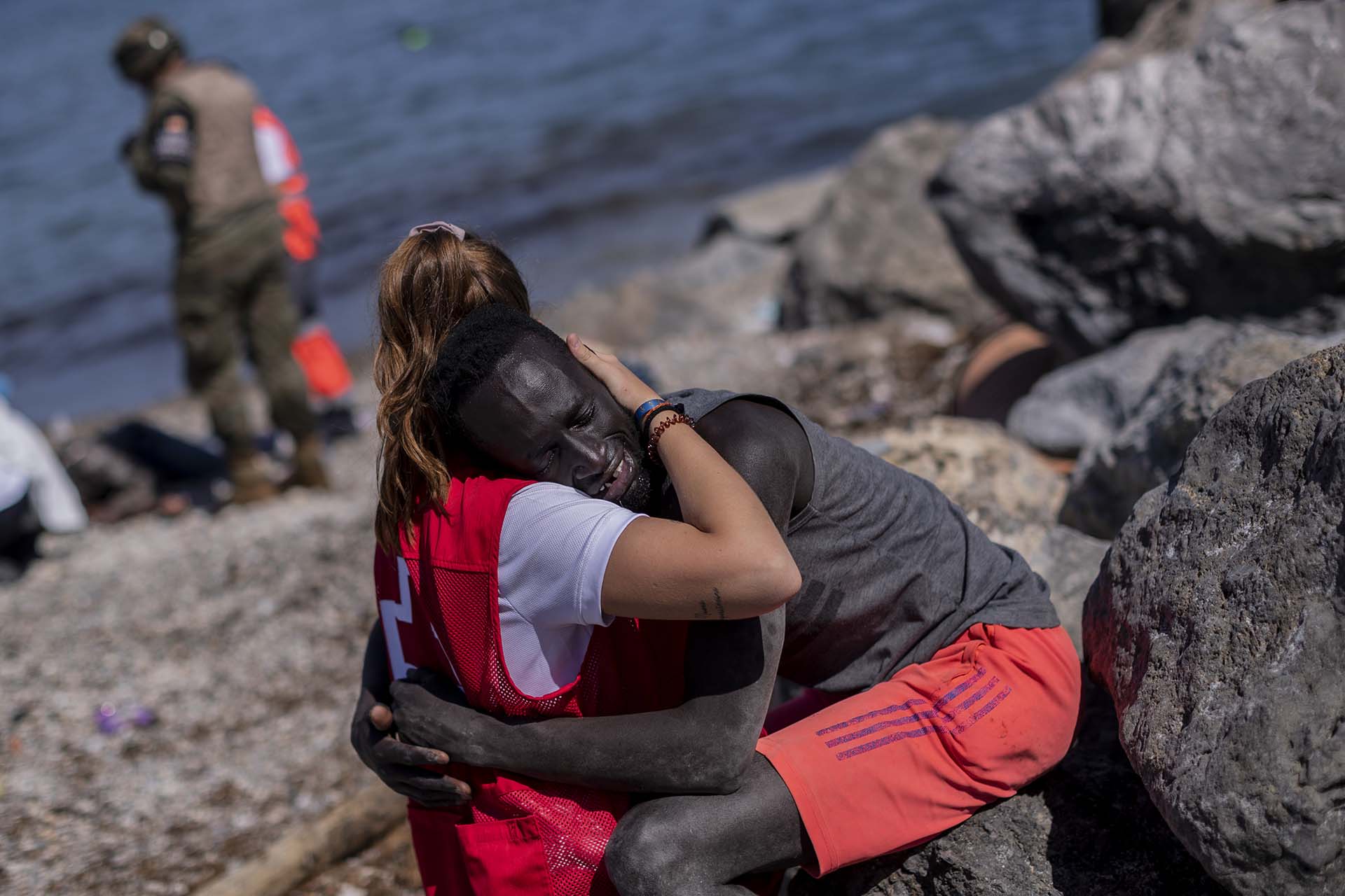 Un migrante es consolado por un miembro de la Cruz Roja española en el enclave español de Ceuta, cerca de la frontera de Marruecos y España, el 18 de mayo de 2021. (AP Photo/Bernat Armangue)