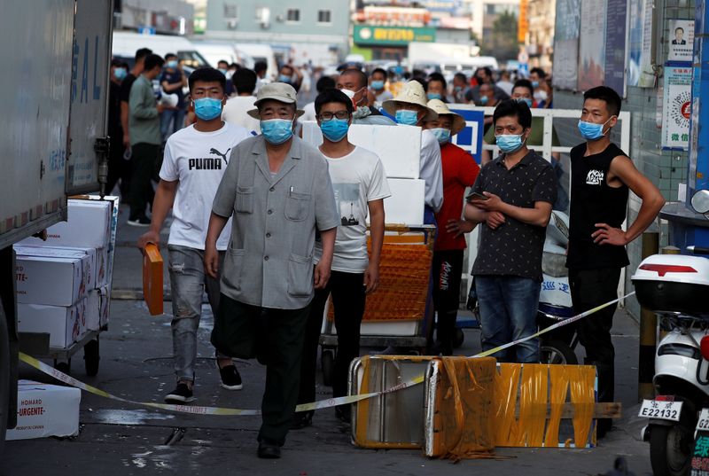 Varios hombres con mascarillas en el interior del mercado de marisco Jingshen, cerrado al comercio tras la detección de nuevas infecciones por coronavirus, en Pekín, China, el 12 de junio de 2020. REUTERS/Thomas Peter