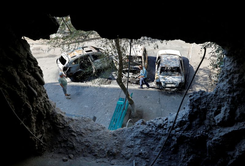 Varias personas inspeccionan unos vehículos destrozados tras unos bombardeos recientes durante la invasión rusa de Ucrania en Energodar, controlada por el ejército ruso, en la región de Zaporiyia, Ucrania, el 30 de agosto de 2022. REUTERS/Alexander Ermochenko