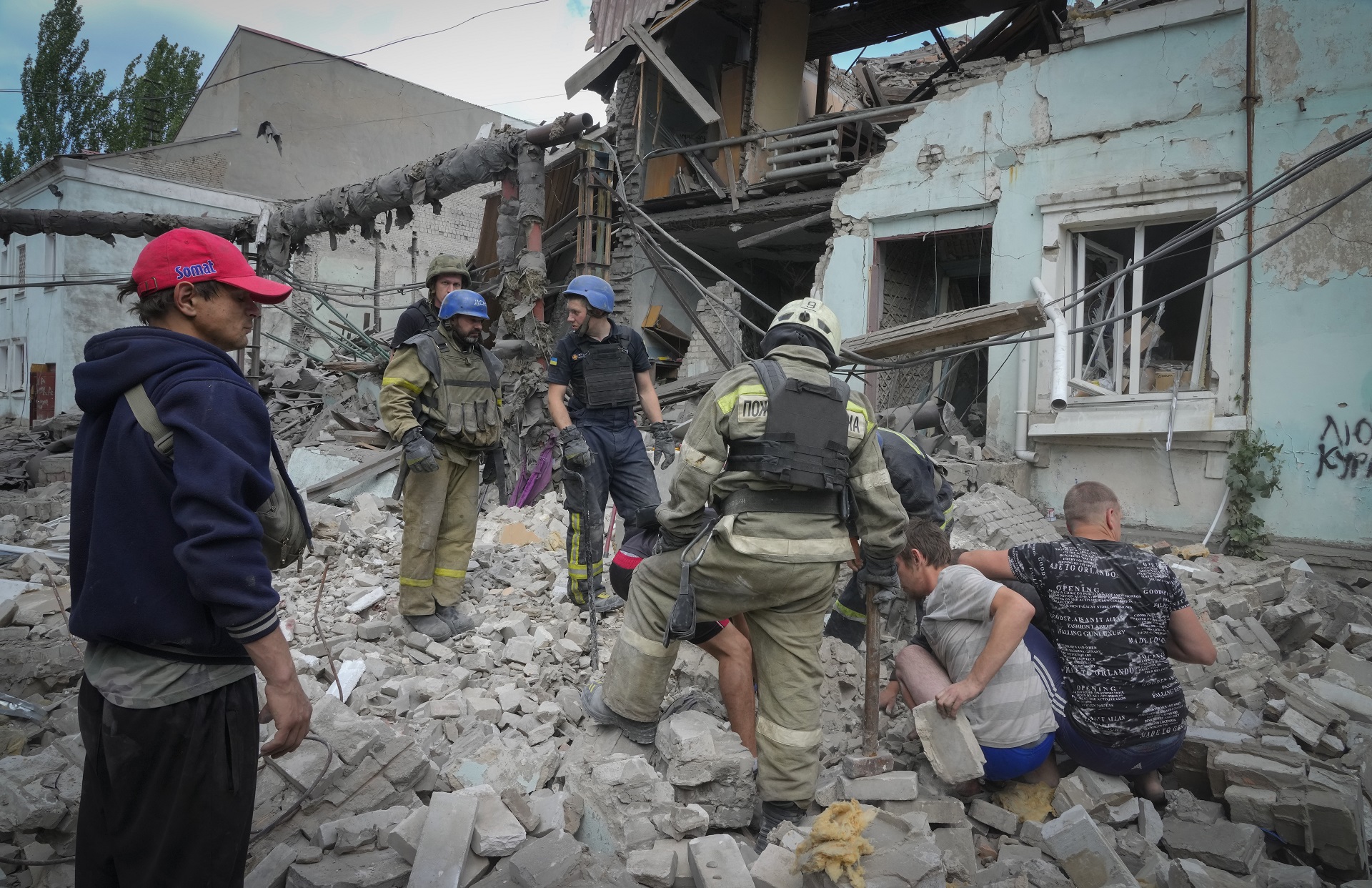 Los trabajadores de búsqueda y rescate y los residentes locales sacan un cuerpo de debajo de los escombros de un edificio después de un ataque aéreo ruso en Lysychansk