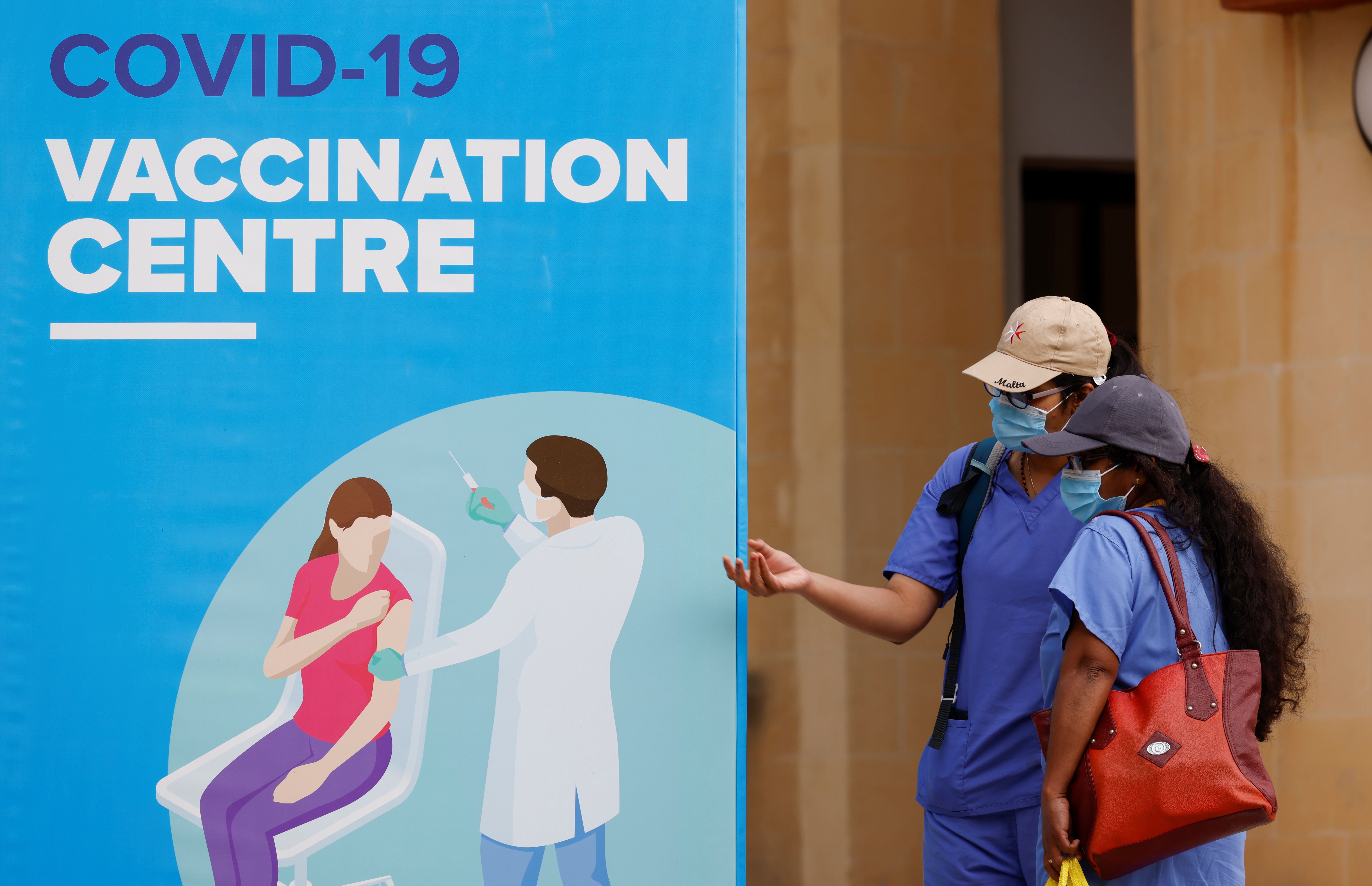 Dos personas conversan en la puerta de un centro de vacunación en la Universidad de Malta el 24 de mayo de 2021. Malta es el país con mayor porcentaje de la población vacunada en el mundo (REUTERS/Darrin Zammit Lupi)