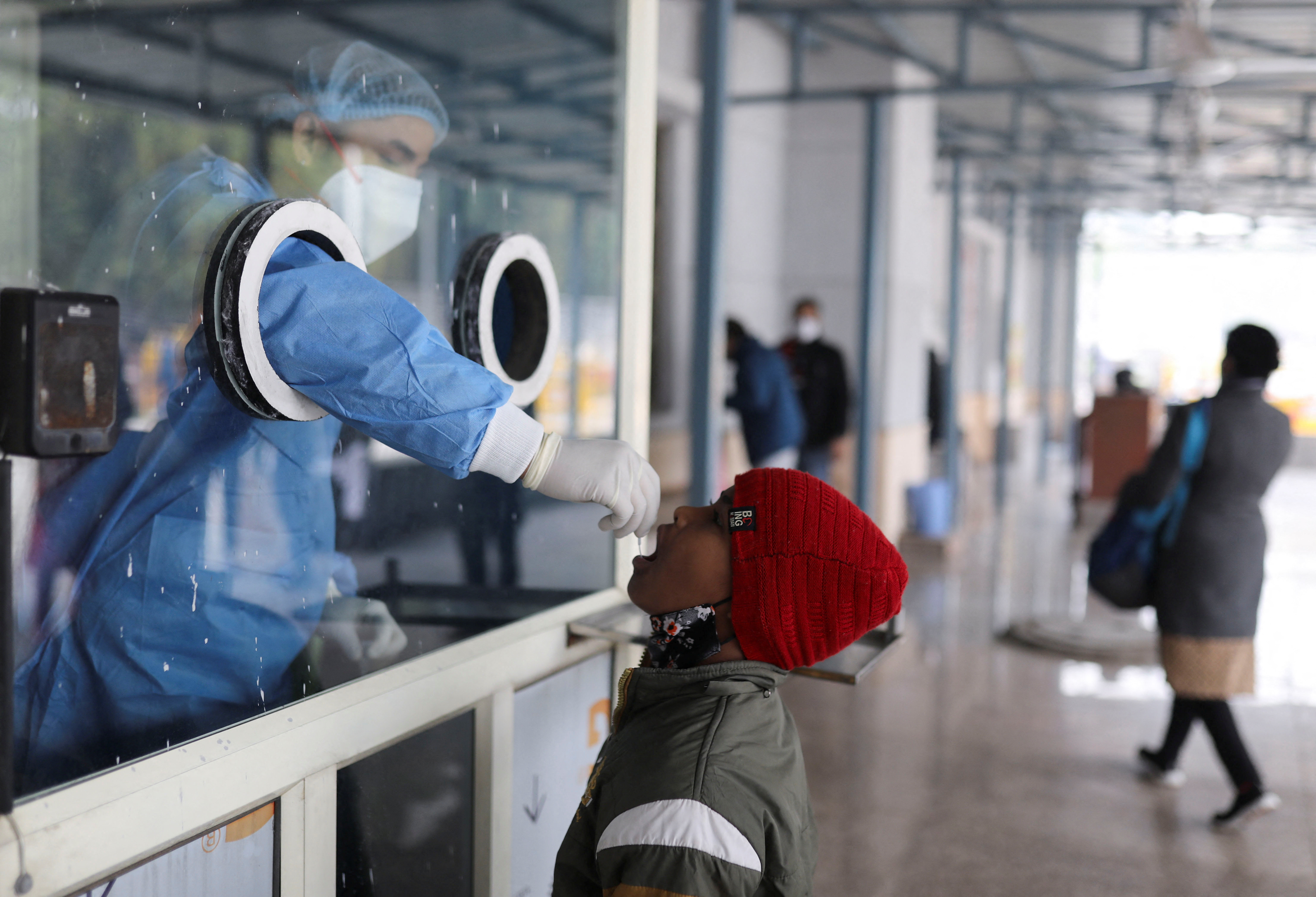 A healthcare worker collects a test swab sample from a child amidst the spread of the coronavirus disease (COVID-19), at a testing centre inside a hospital in New Delhi, India, January 14, 2022. REUTERS/Anushree Fadnavis