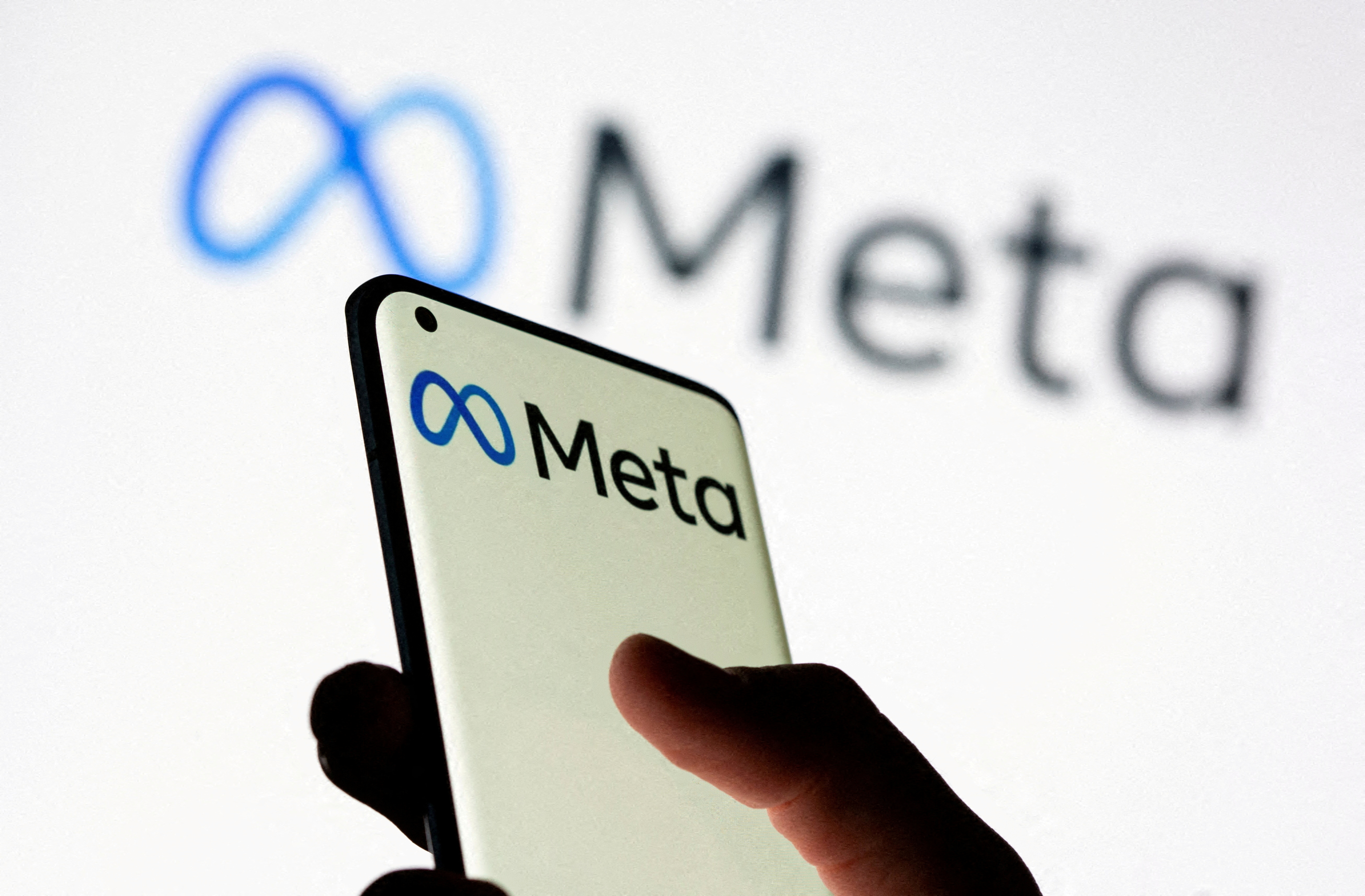 FILE PHOTO: A woman holds smartphone with Meta logo in front of a displayed Facebook's new rebrand logo Meta in this illustration picture taken October 28, 2021. REUTERS/Dado Ruvic//File Photo