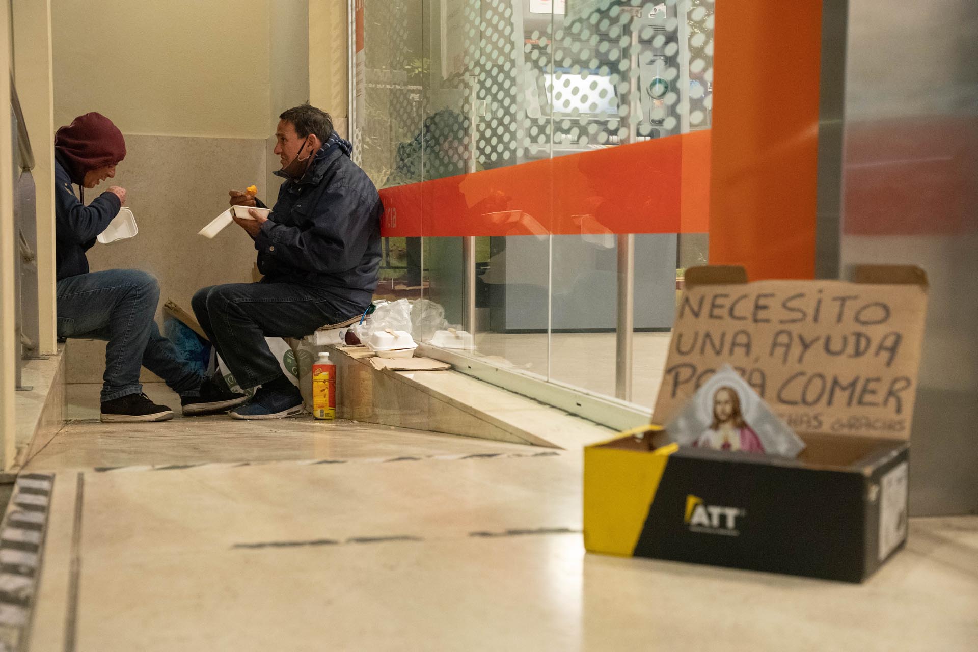 Dos personas cenan en la entrada a un banco en la ciudad de Buenos Aires durante el invierno de 2022, para la misma época que se realizó el Censo 