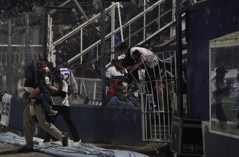 Los hinchas afectados por las gases lacrimógenos que arrojó la policía, saltaron al campo de juego (REUTERS/José Brusco)