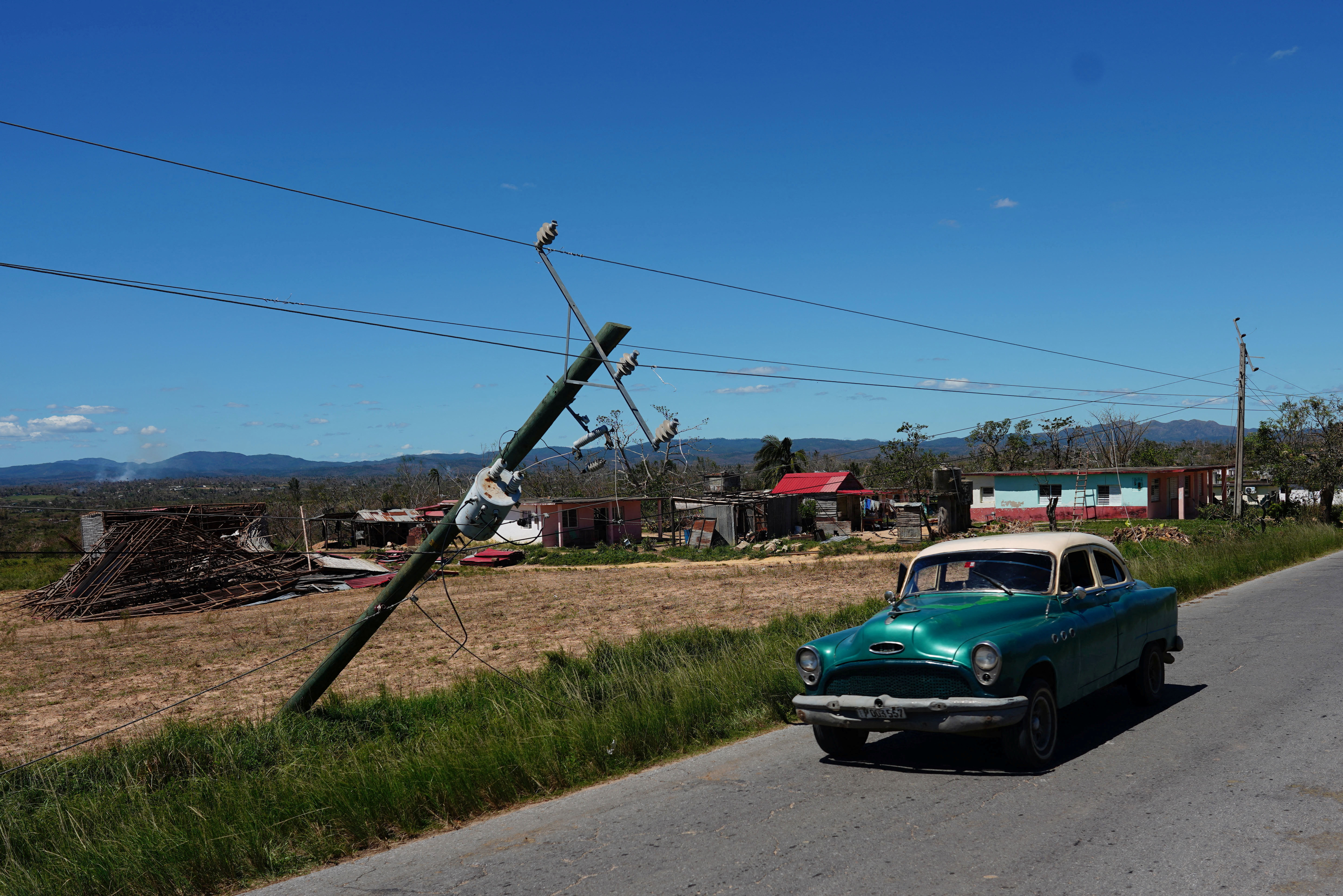 Un auto pasa junto a un poste de luz dañado (REUTERS/Alexandre Meneghini)