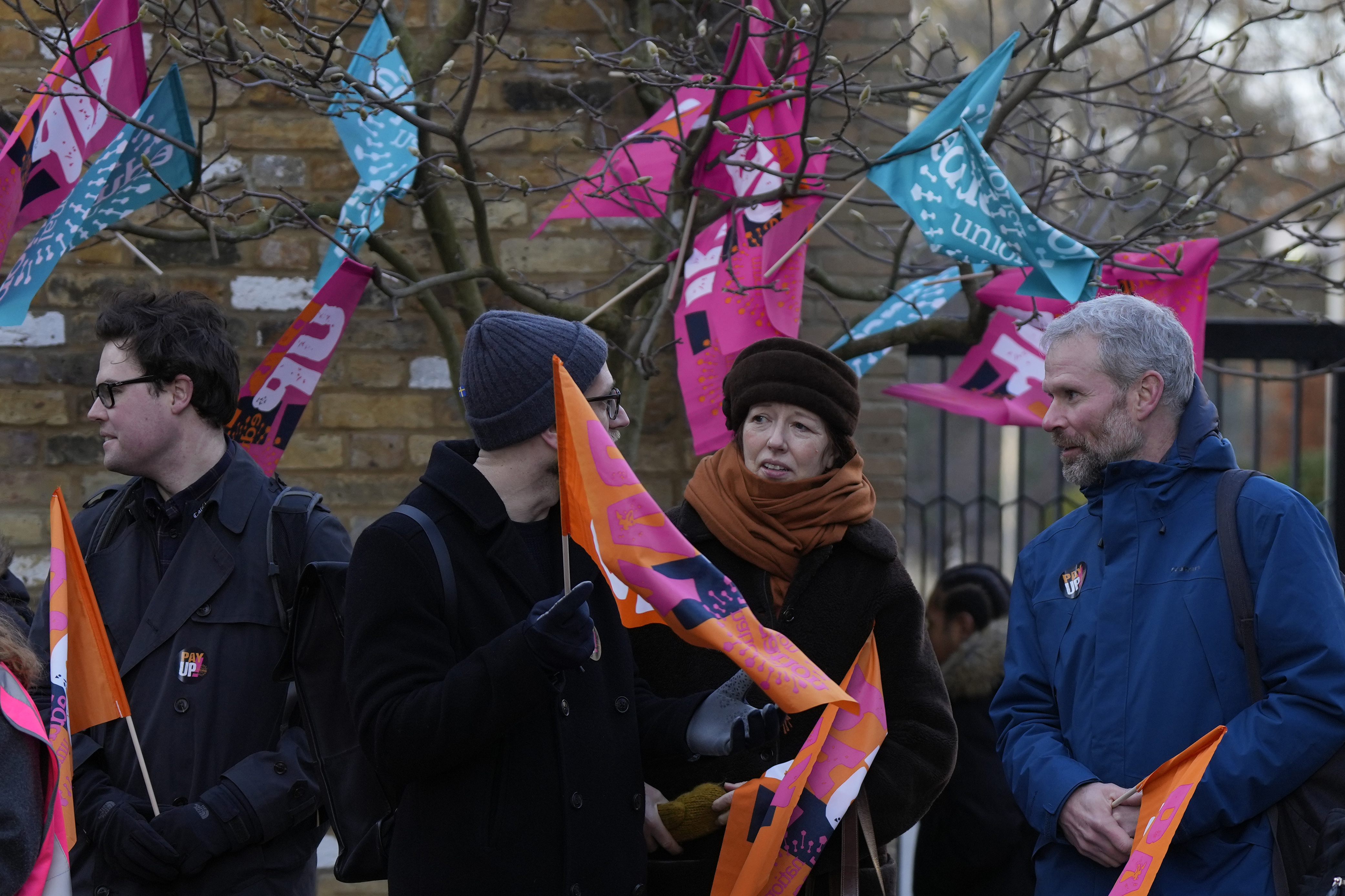Teachers hold flags and banners outside Holland Park School during a strike over wages in London on Feb. 1, 2023. (AP Photo/Alastair Grant)