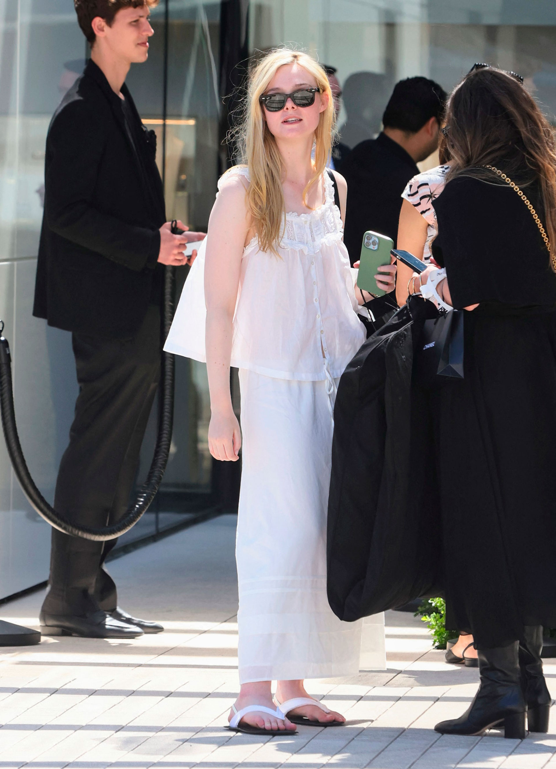Día de compras. Elle Fanning fue fotografiada en el centro comercial de Rodeo Drive, Beverly Hills, Los Ángeles. Allí, recorrió las tiendas más exclusivas y se detuvo particularmente en Dior. Lució un conjunto de musculosa y pollera de lino color blanco que combinó con sus ojotas de cuero
