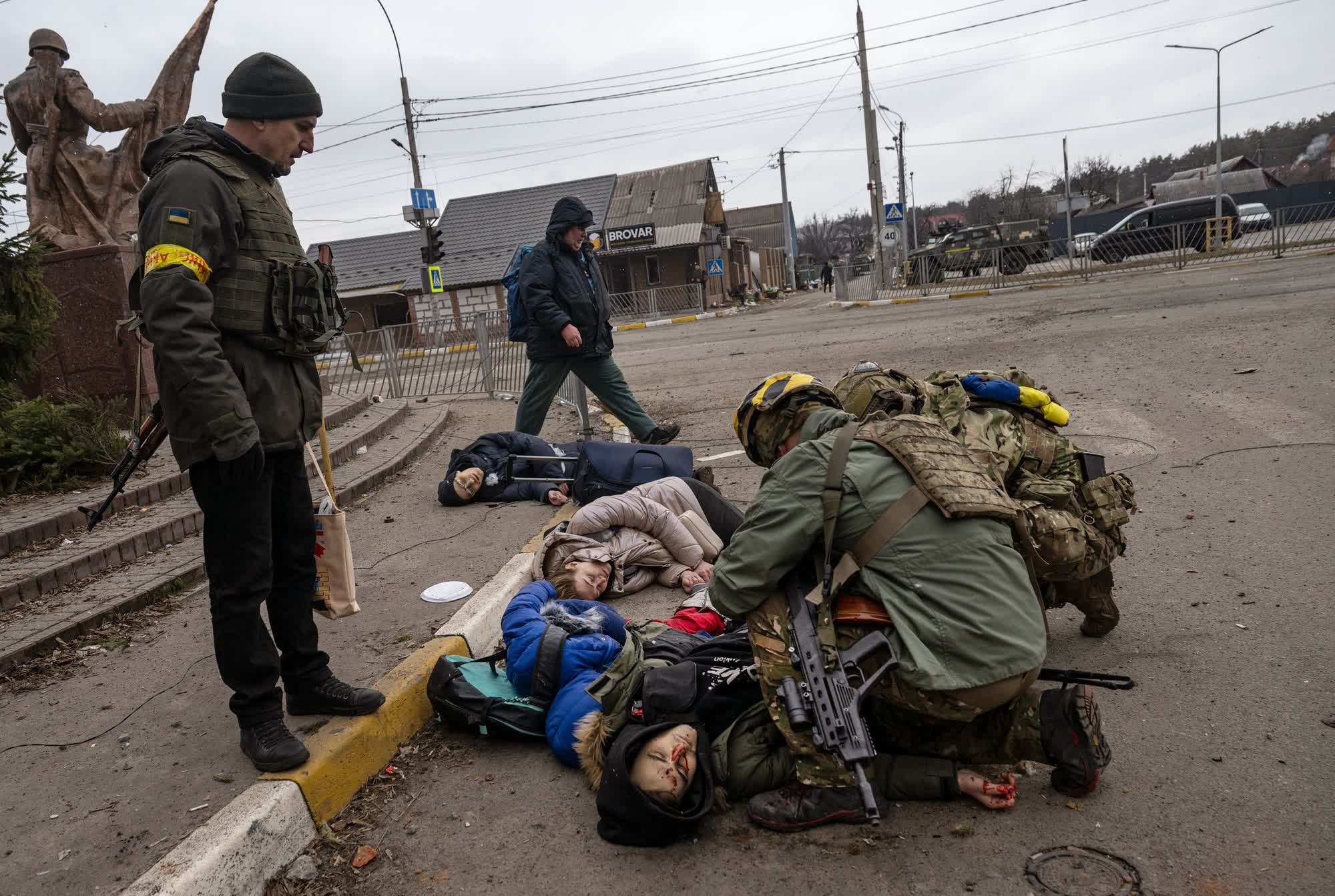 Tetiana Perbyinis y sus dos hijos yacen muertos tras ser alcanzados por un misil mientras un soldado trata de ayudar a otra persona que resultó herida en un ataque en la localidad de Irpin. (Linsey Addario/Reuters)
