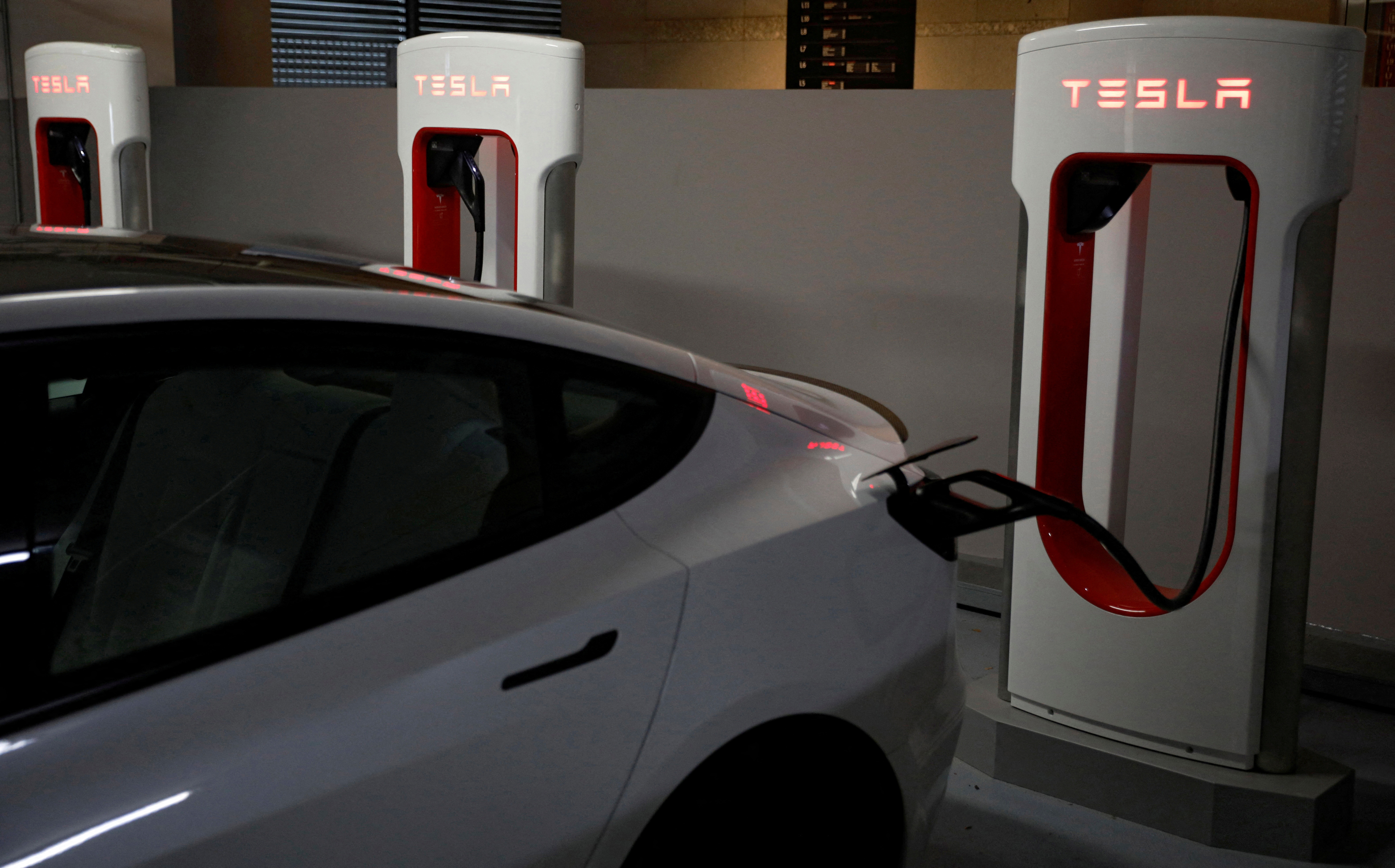 FILE PHOTO: A Tesla car charges at a Supercharger station in Singapore October 22, 2021. Picture taken October 22, 2021. REUTERS/Edgar Su/File Photo