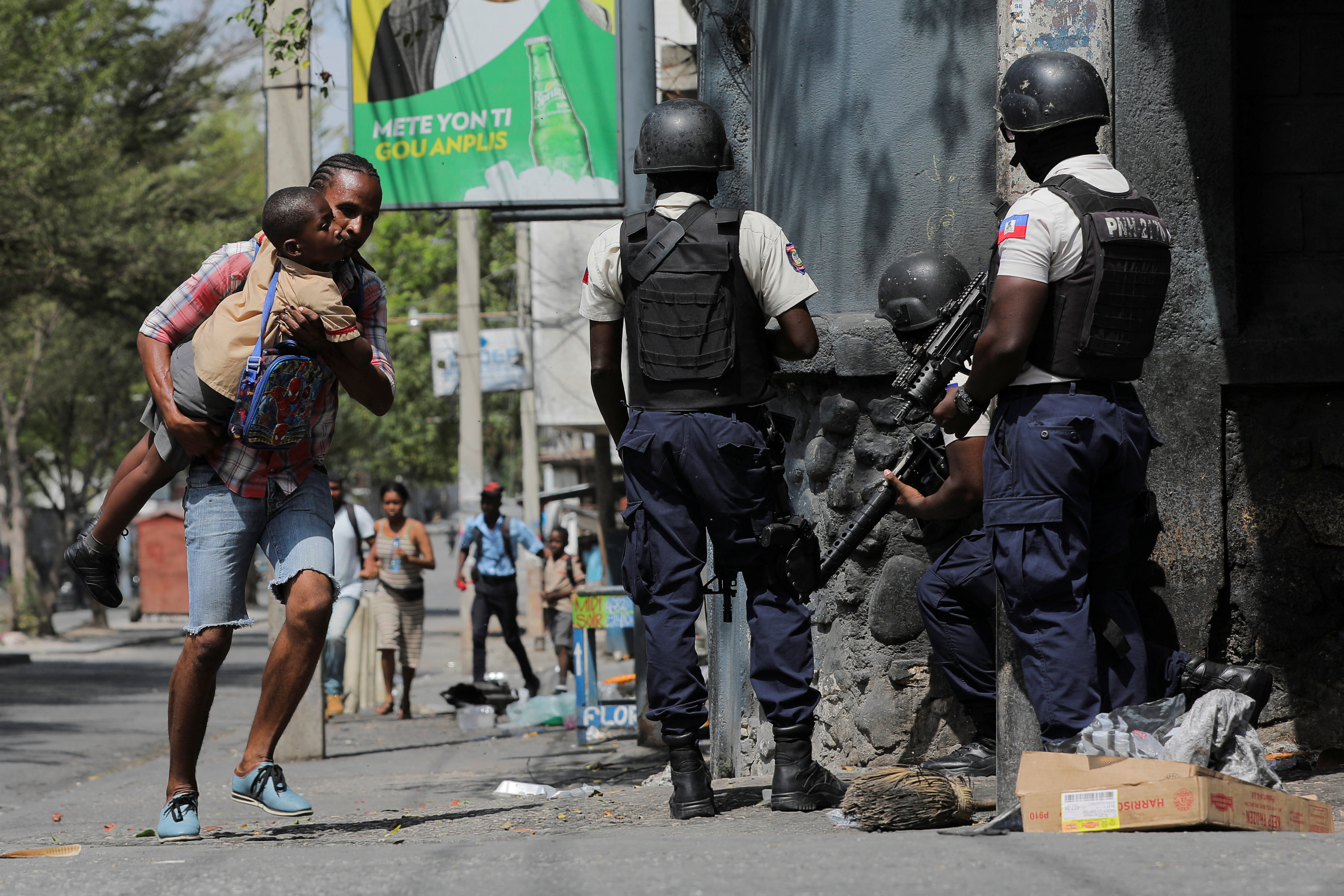 Un hombre lleva a su hijo en brazos mientras buscan refugio tras salir de la escuela en medio de la violencia de bandas en Puerto Príncipe (REUTERS/Ralph Tedy Erol)
