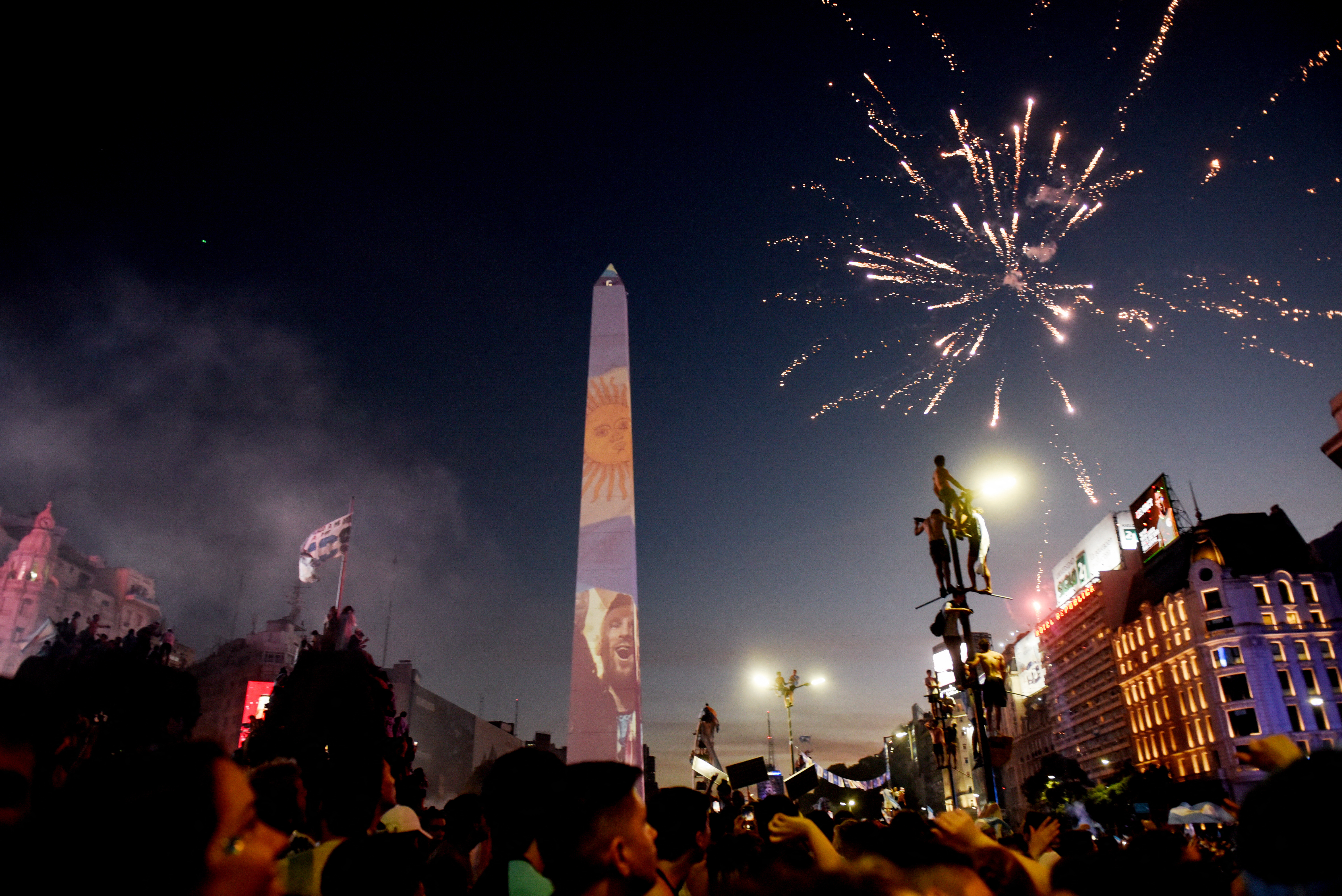 Soccer Football - FIFA World Cup Final Qatar 2022 - Fans in Buenos Aires - Buenos Aires, Argentina - December 18, 2022  Argentina fans celebrate winning the World Cup at the Obelisk with an image of Lionel Messi and fireworks REUTERS/Mariana Nedelcu