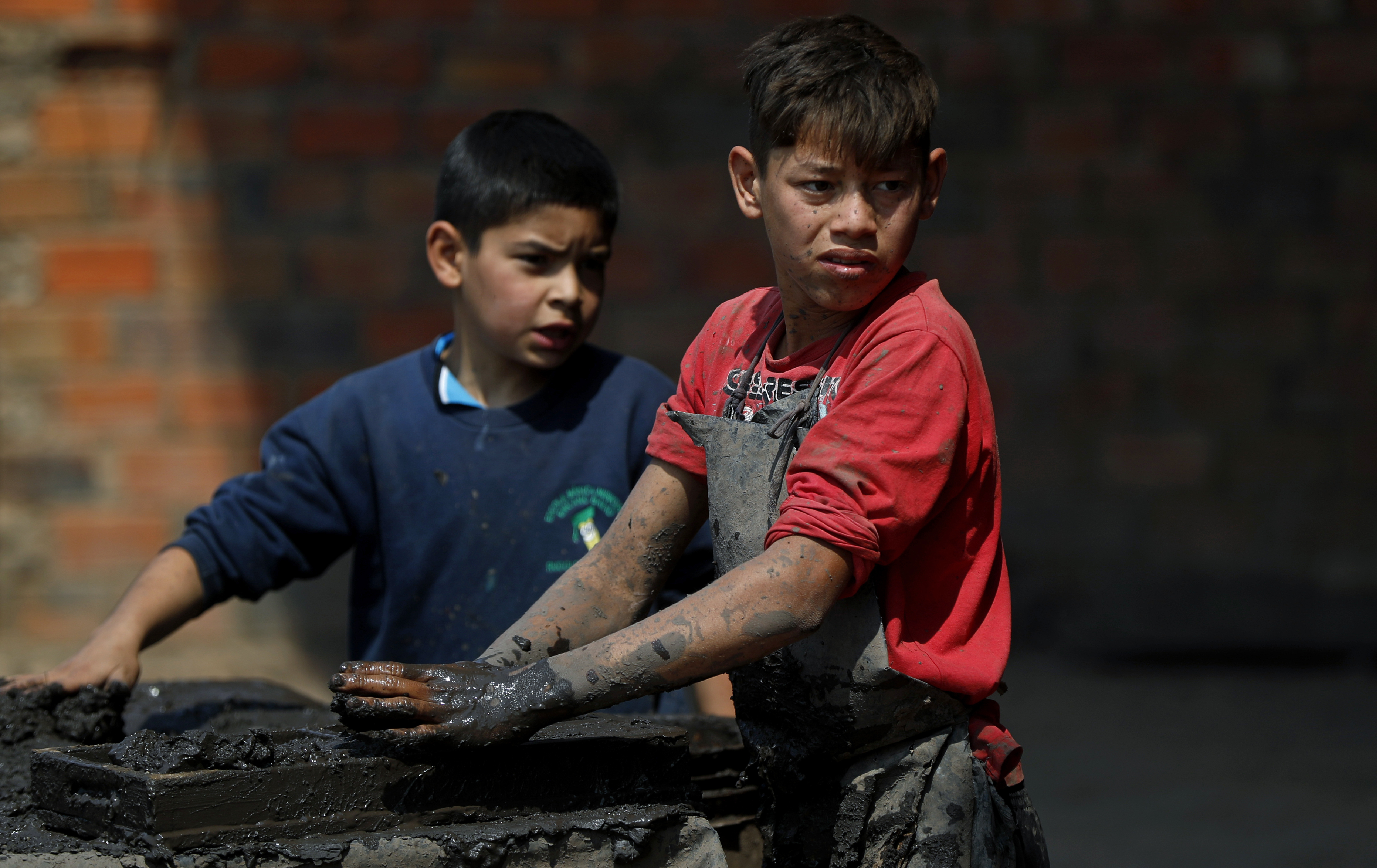 Mauri, 11, izquierda, y Cesar, 13, trabajan en una fábrica de ladrillos de arcilla en Tobati, Paraguay, el viernes 4 de septiembre de 2020.