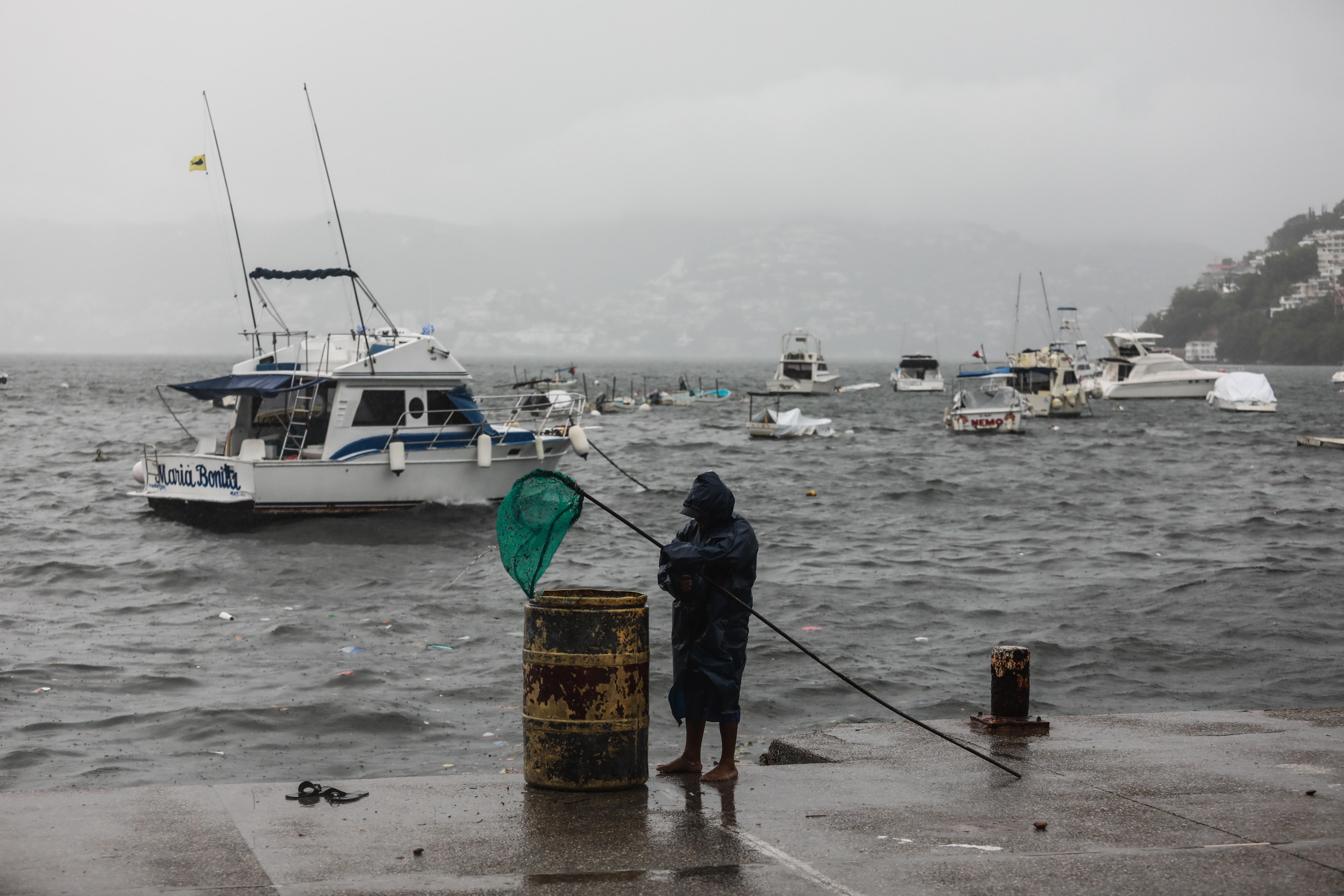 Un hombre sostiene una caña de pescar de red en el malecón de Acapulco, el cual se encuentra cerrado a la navegación debido a la tormenta tropical Enrique, en Acapulco, estado de Guerrero (México). EFE/ David Guzmán
