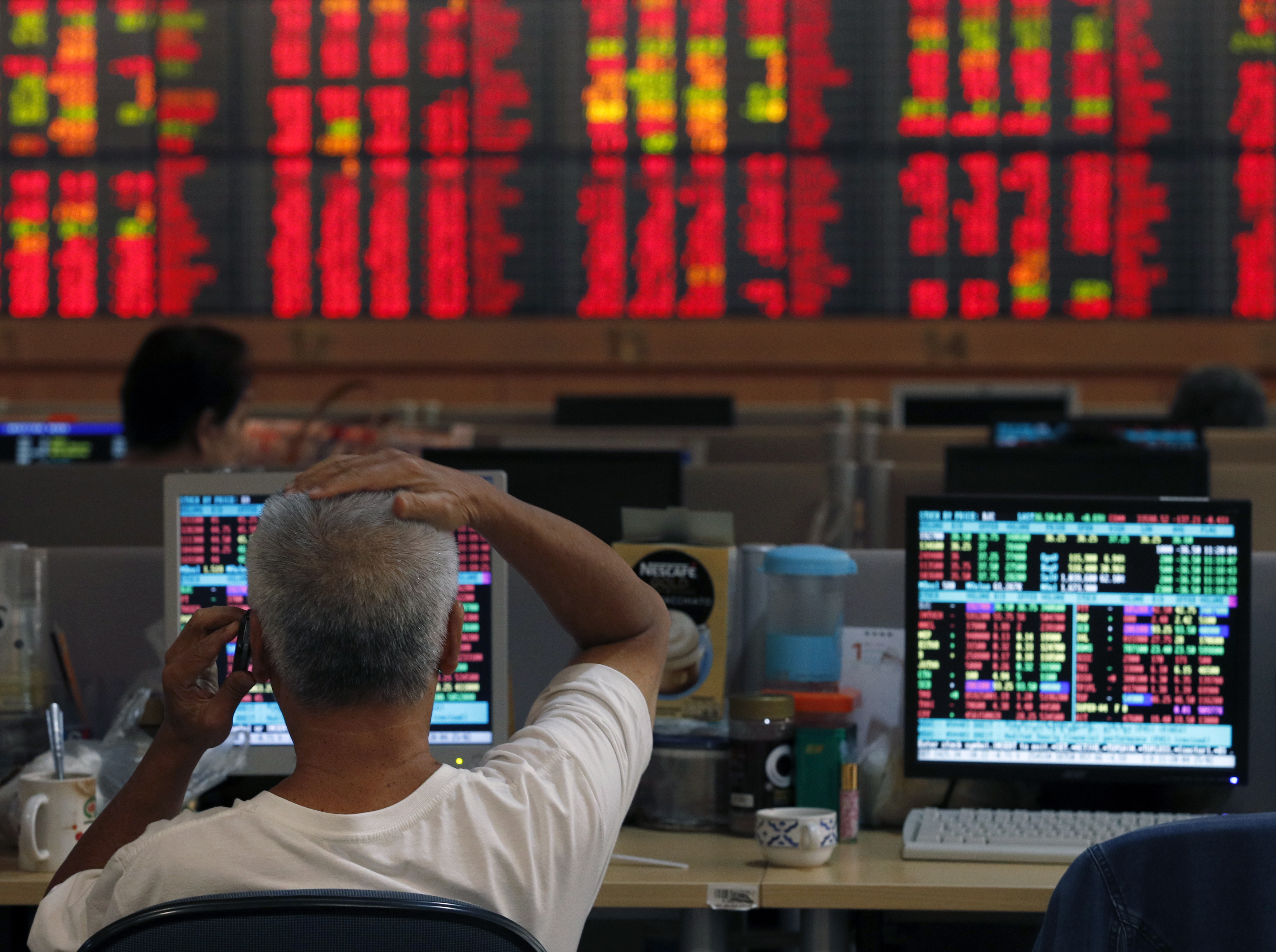 Un operador de Wall Street con pantallas en rojo de fondo
