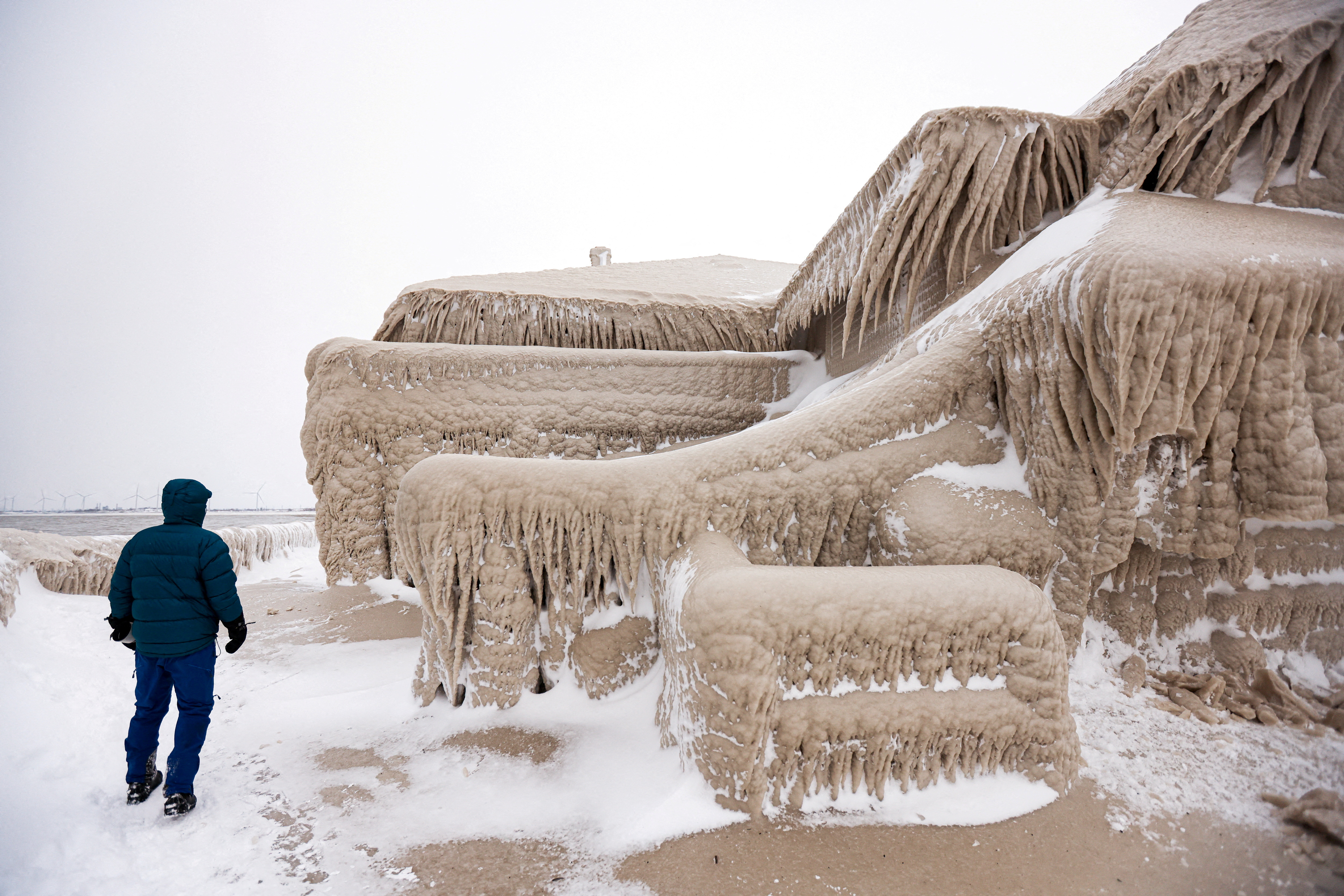 Un hombre camina junto al hielo formado por las olas del lago Erie que cubrieron un restaurante durante una tormenta de invierno en Hamburgo, Nueva York.
