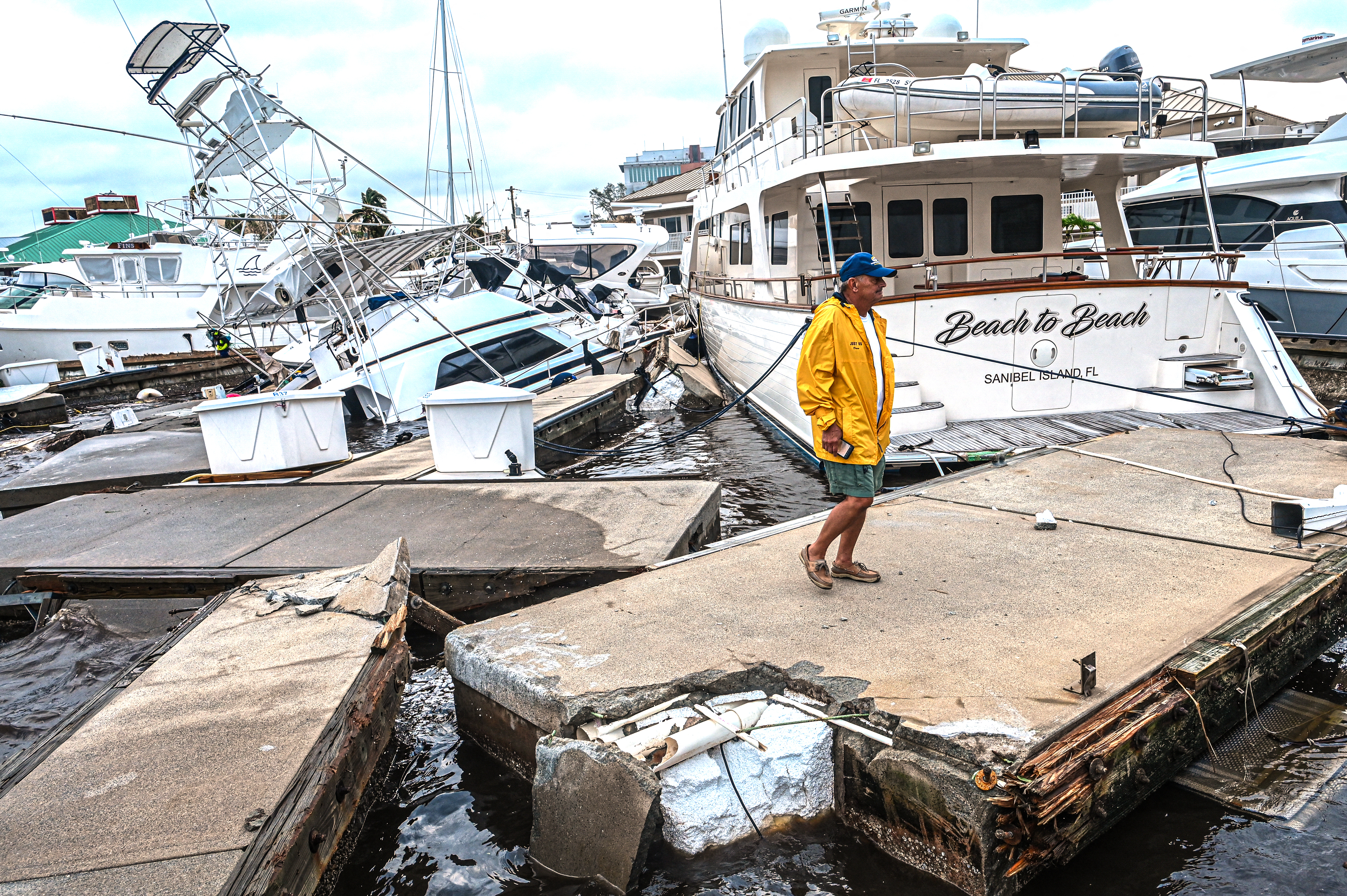 Un hombre inspecciona los daños a un puerto deportivo mientras los barcos están parcialmente sumergidos después del huracán Ian en Fort Myers, Florida, el 29 de septiembre de 2022. (Giorgio VIERA / AFP)