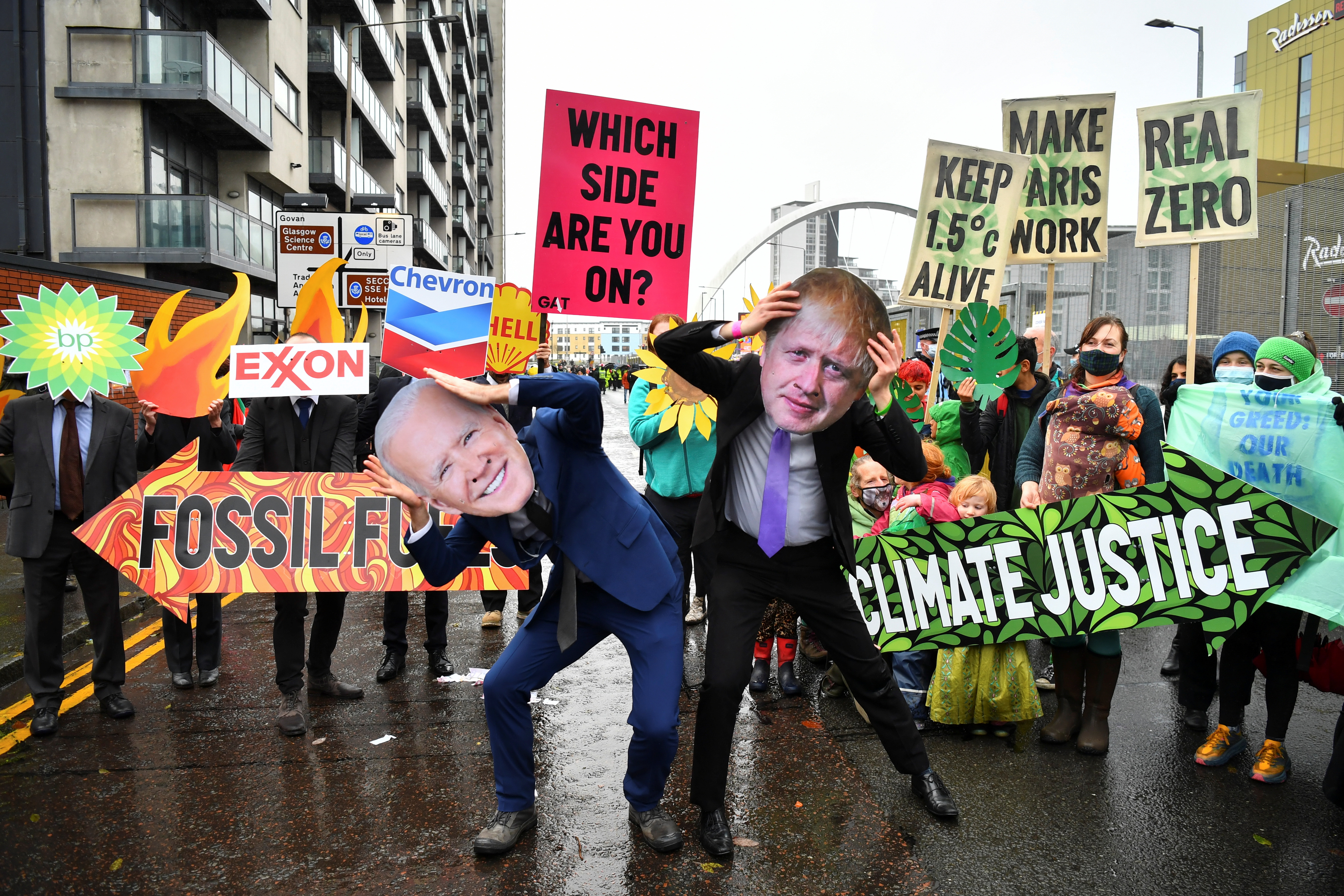 Activistas de un grupo ambientalista se manifiesta con máscaras de Biden y Johnson en las afueras del recinto donde se desarrolló la COP26, en Glasgow (REUTERS/Dylan Martinez)
