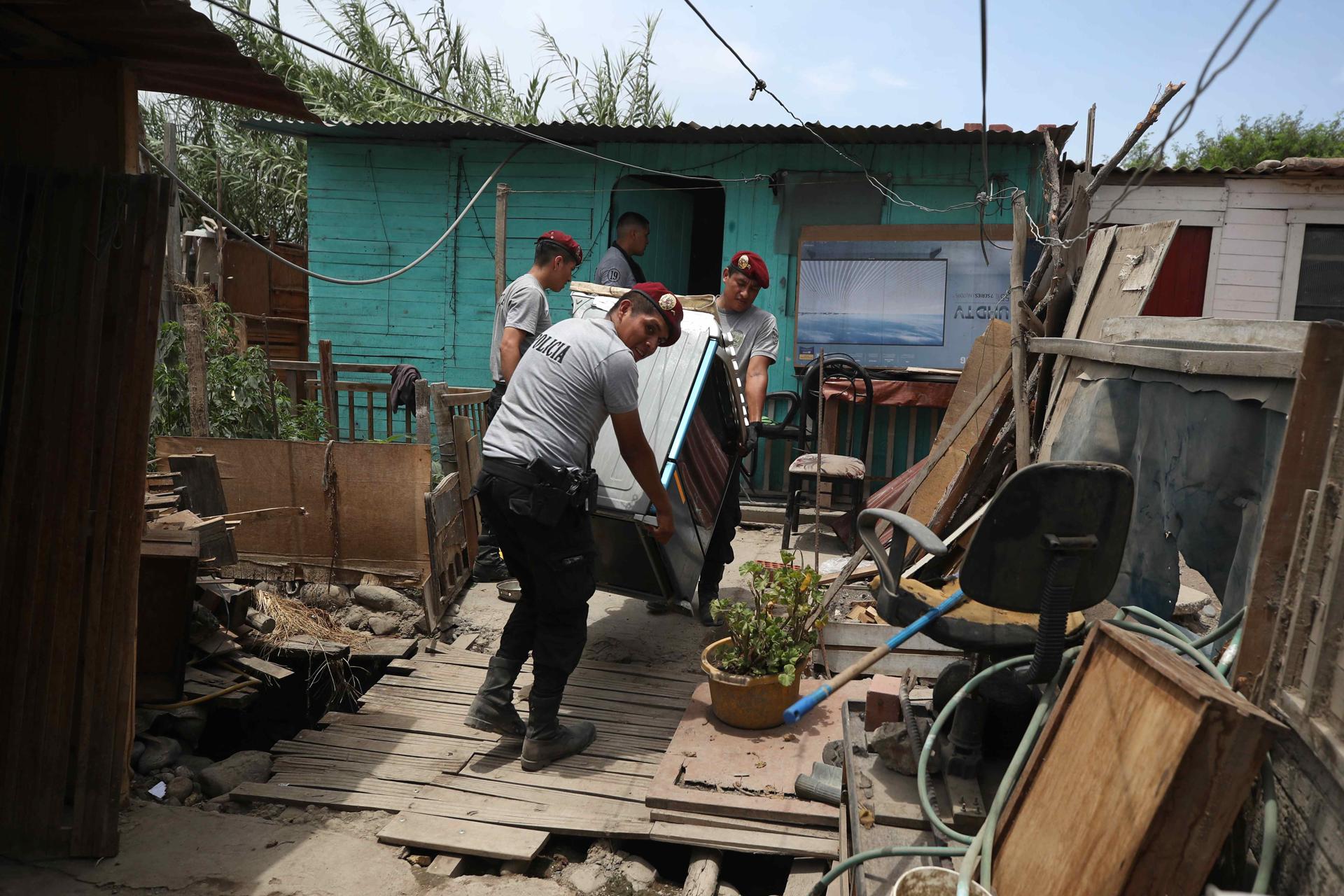 AME2038. LIMA (PERÚ), 13/03/2023.- Policías ayudan a recuperar pertenencias en las viviendas de habitantes afectados por el desborde del río Chillón, hoy, en Lima (Perú). El desborde del río Chillón en el distrito limeño de Puente Piedra provocó este lunes la destrucción de unas 25 casas rústicas que se encontraban cerca de la orilla, primera consecuencia en la capital peruana de las lluvias generadas por la presencia del ciclón Yaku frente a la costa. EFE/ Paolo Aguilar
