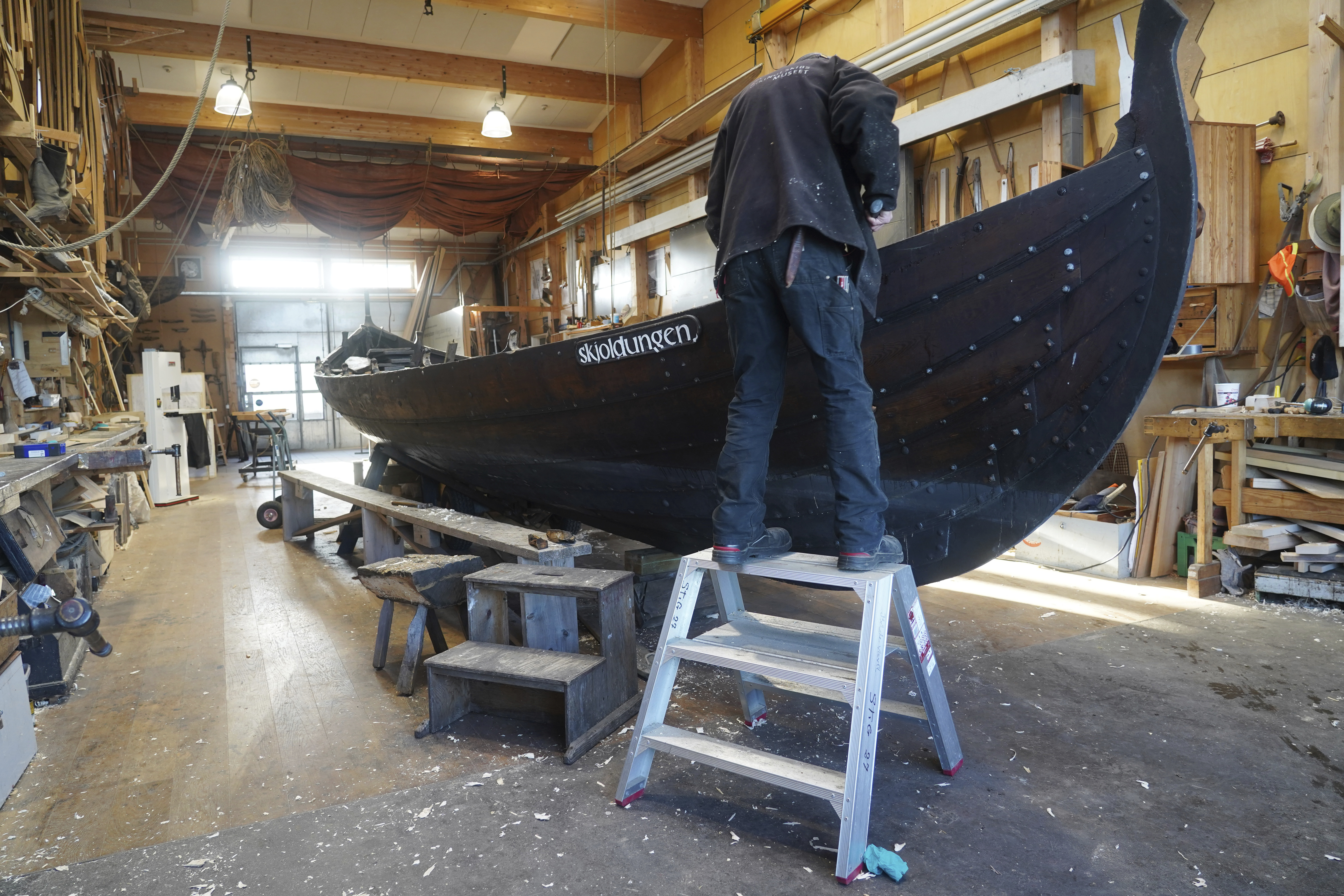 Un hombre repara un bote de remos de madera de 10 metros, construido según la tradición nórdica de los botes de escoria, en el astillero del Museo de Barcos Vikingos. Roskilde, Dinamarca, lunes 17 de enero de 2022. (Foto AP/James Brooks)

