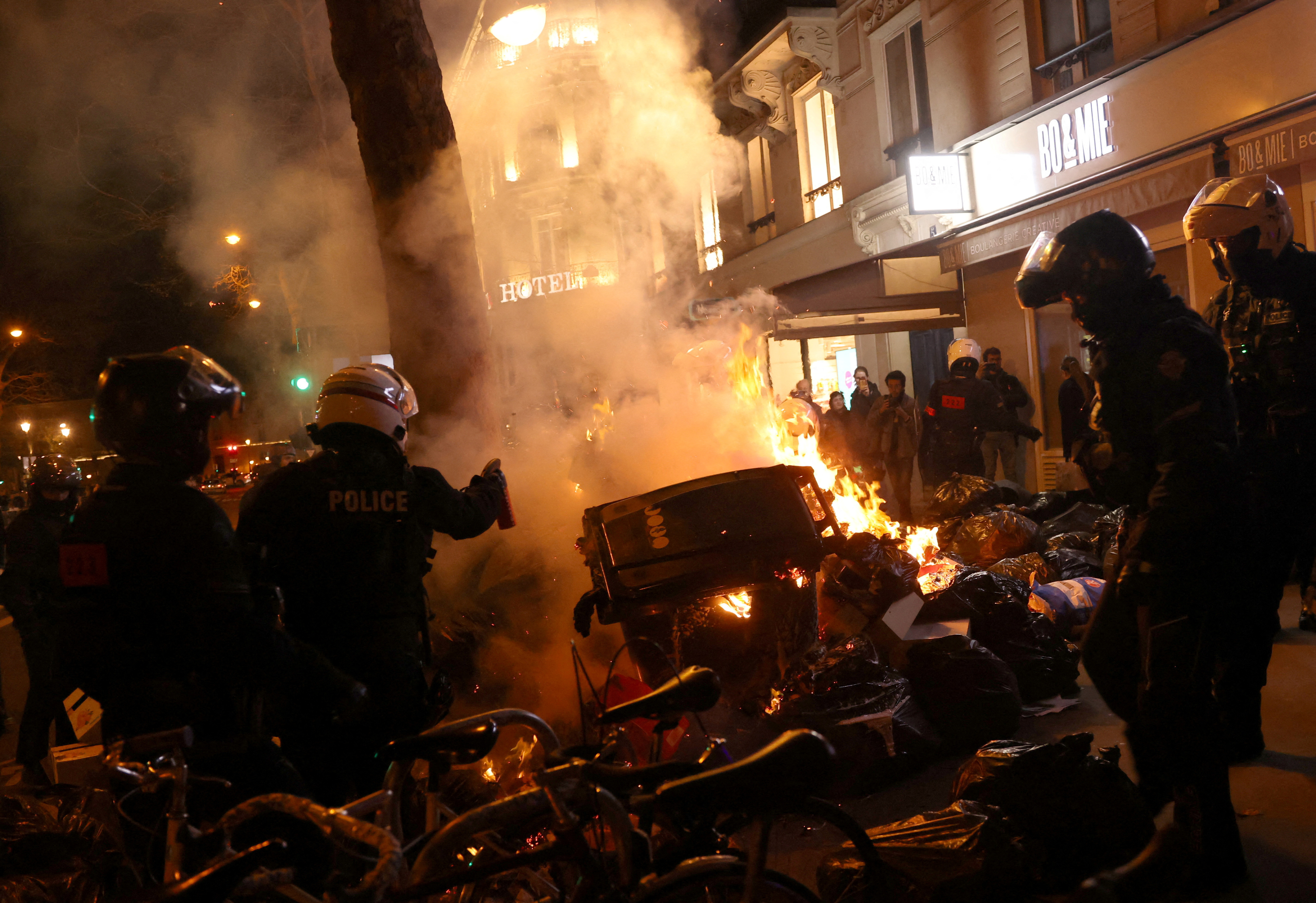 La policía antidisturbios francesa intenta extinguir un incendio en medio de enfrentamientos durante una manifestación contra la reforma de las pensiones impulsada por el Gobierno, en París (REUTERS/Nacho Doce)