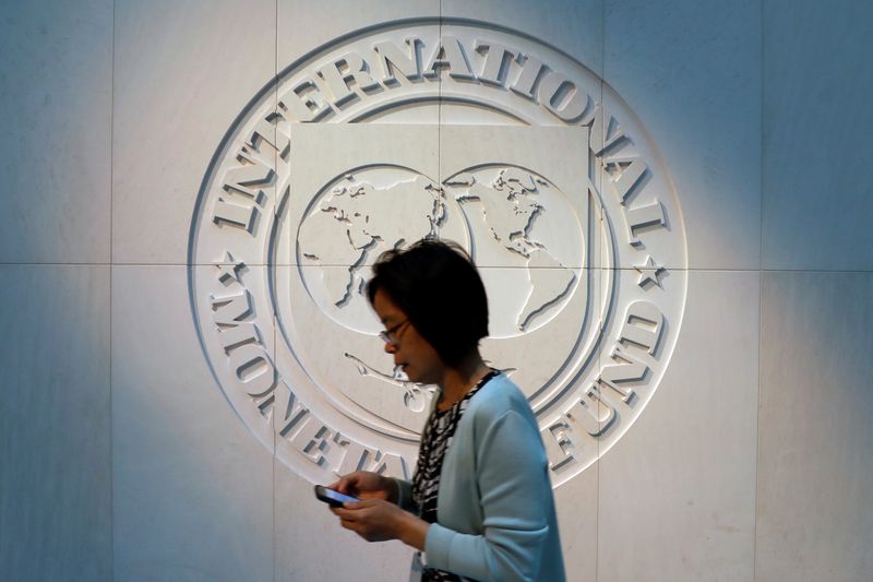 FOTO DE ARCHIVO. Una mujer pasa frente al logo del Fondo Monetario Internacional (FMI), en su sede en Washington DC, EEUU. Foto: REUTERS/Yuri Gripas