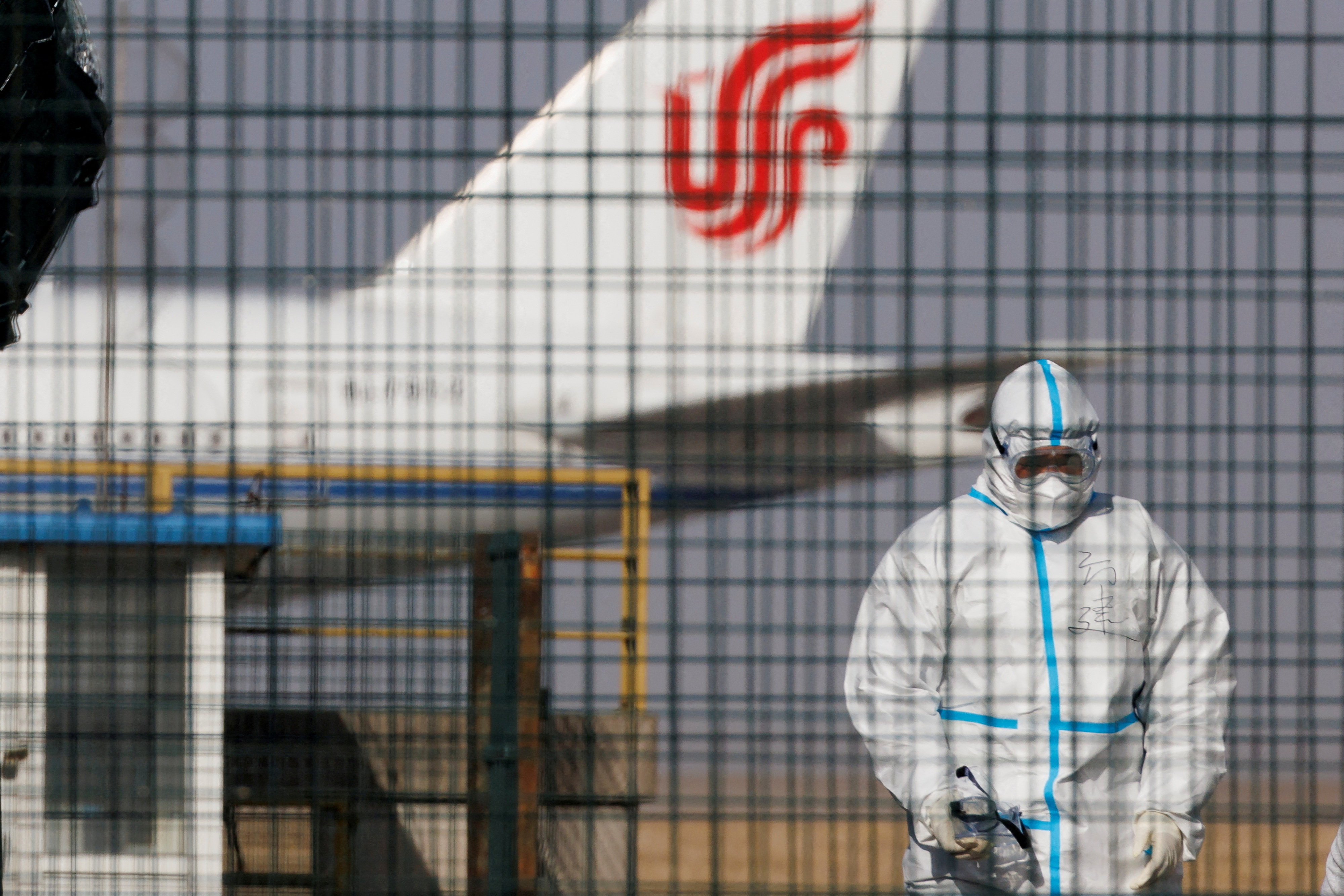 Un empleado en traje sanitario, con un avión de Air China de fondo en Beijing (Reuters)