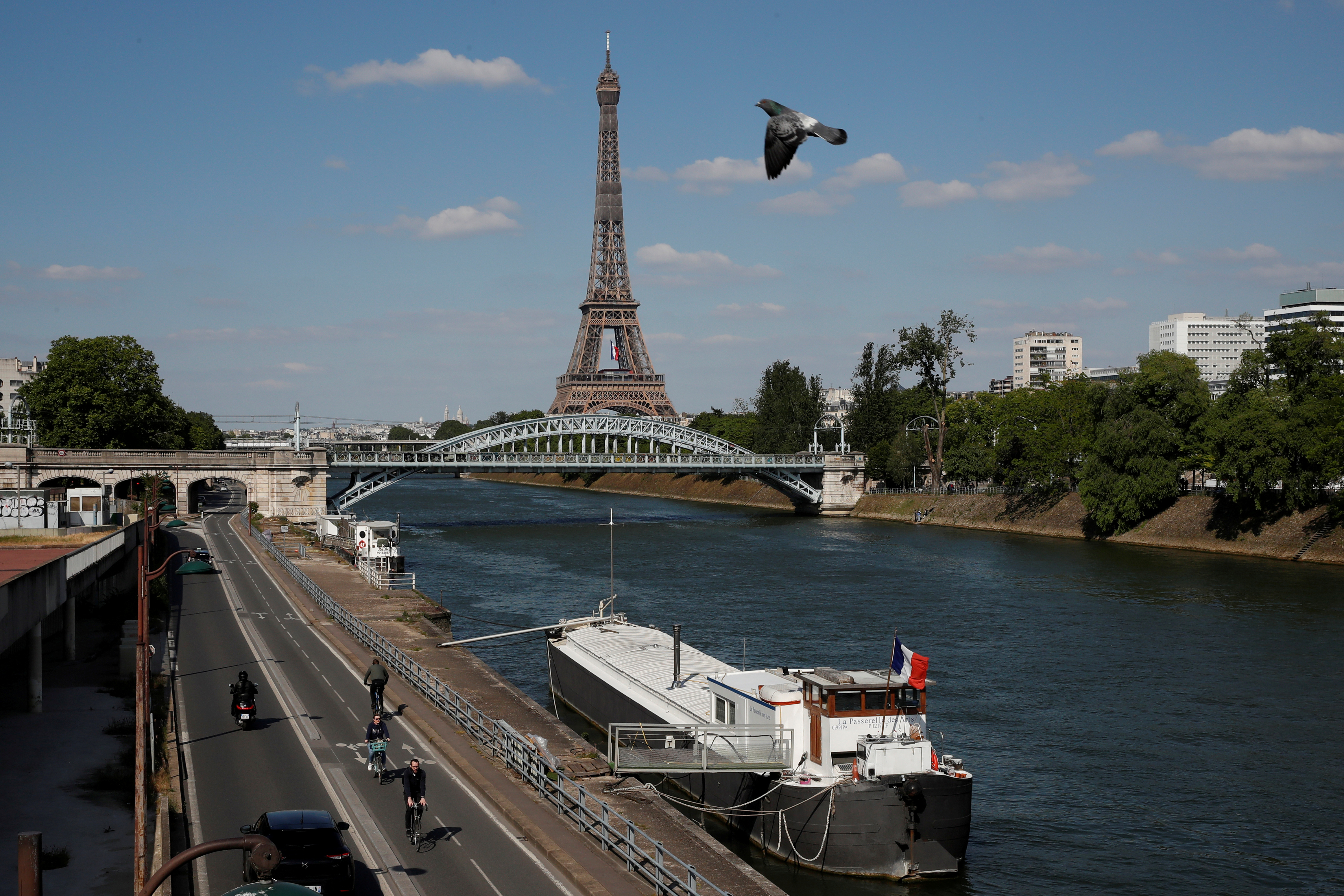 FILE PHOTO: People ride bicycles on a bike path on the banks of the river Seine with the Pont Rouelle bridge and the Eiffel tower in the background in Paris, France, May 14, 2020. REUTERS/Gonzalo Fuentes/File Photo