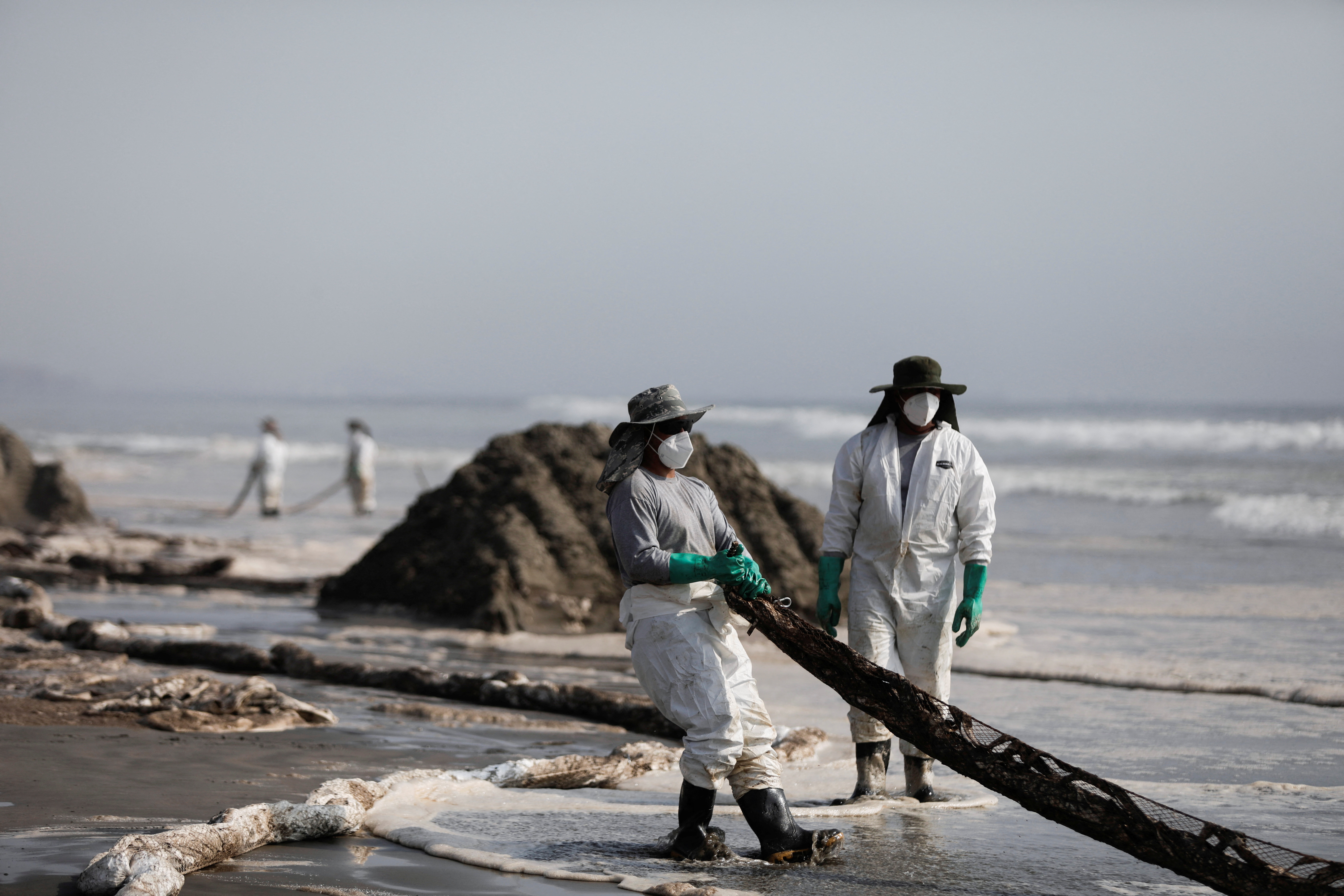 Workers clean an oil spill caused by abnormal waves, triggered by a massive underwater volcanic eruption in Tonga, off the coast of Lima, in Ventanilla, Peru January 19, 2022. REUTERS/Angela Ponce