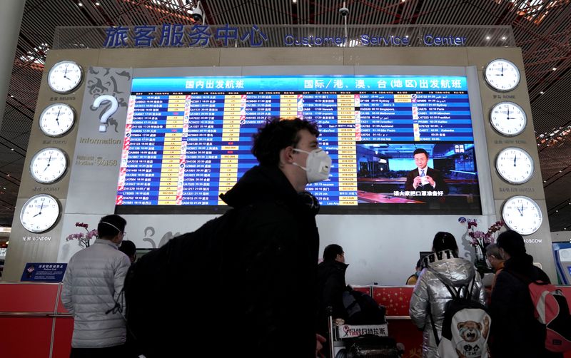 Un viajero extranjero con una máscara pasa por un panel de información de salidas en el aeropuerto internacional de Pekín, China, mientras el país se ve afectado por un brote del nuevo coronavirus, el 1 de febrero, 2020. REUTERS/Jason Lee