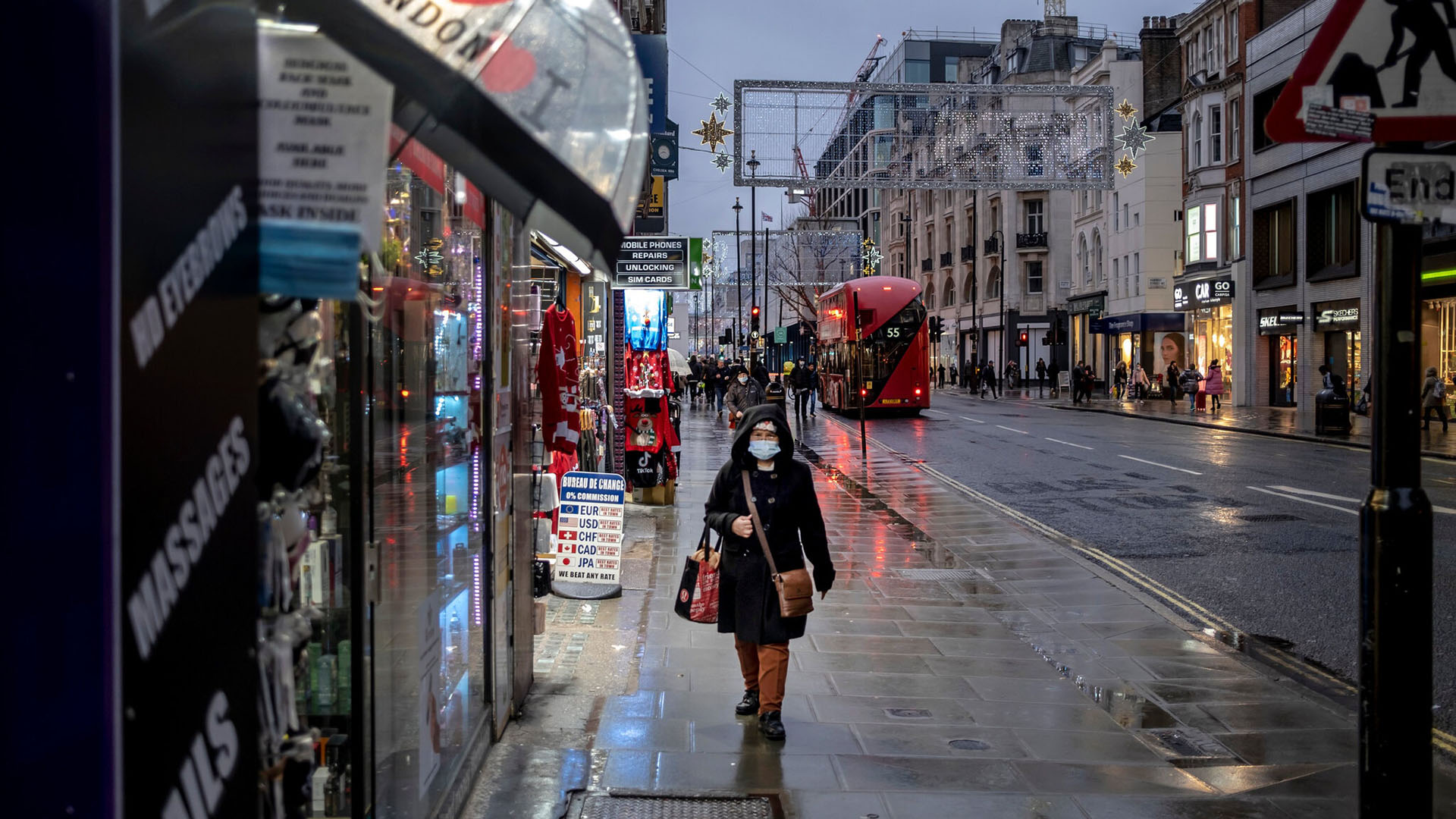 Una mujer camina por una calle húmeda por la lluvia en Oxford el primer día de restricciones de nivel 3 en Londres, el 16 de diciembre de 2020. (Andrew Testa/The New York Times)