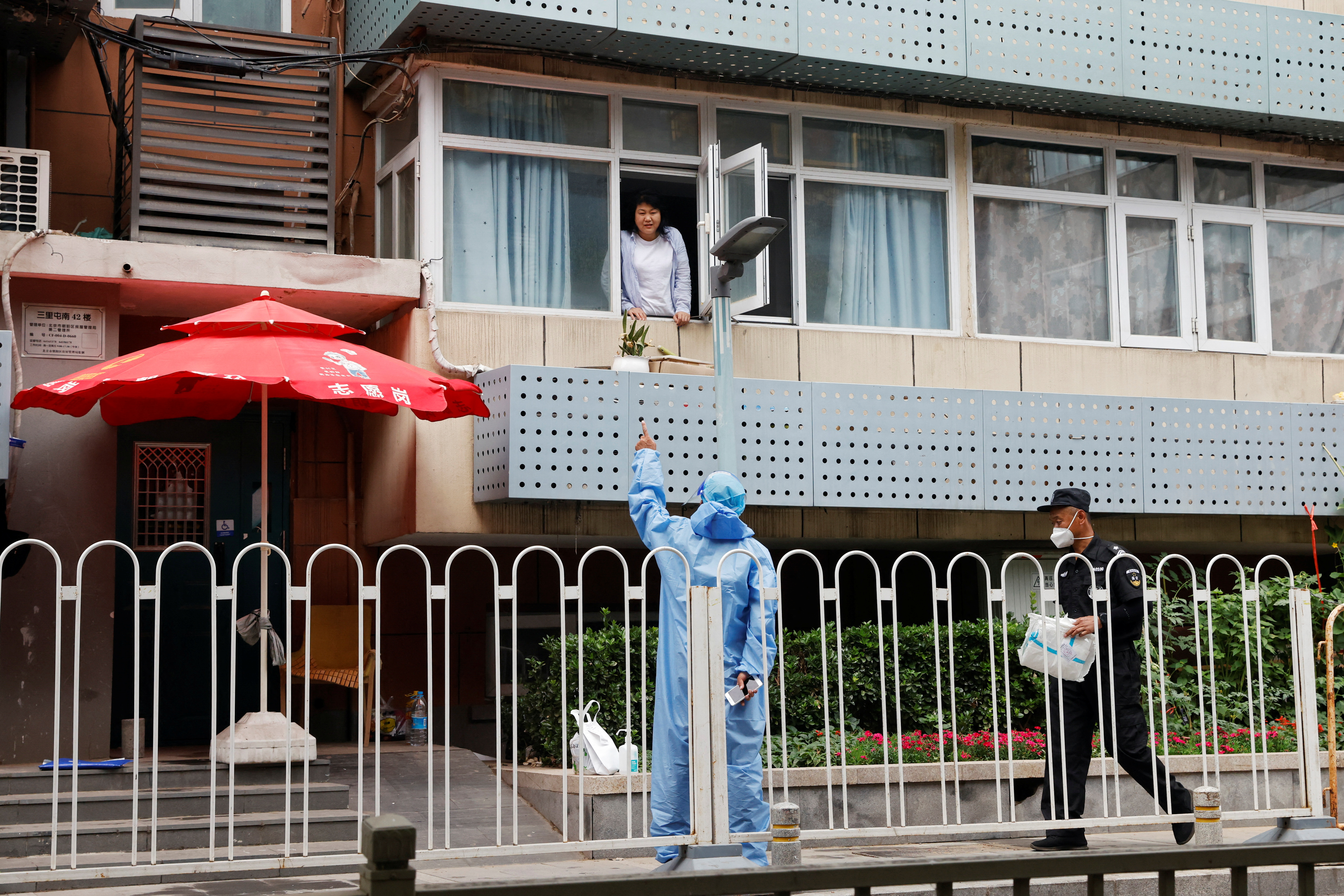 Un residente habla con un trabajador que lleva un traje de protección en un edificio residencial bajo confinamiento, en medio del brote de la enfermedad por coronavirus (COVID-19) en Pekín, China, el 13 de junio de 2022. REUTERS/Carlos Garcia Rawlins